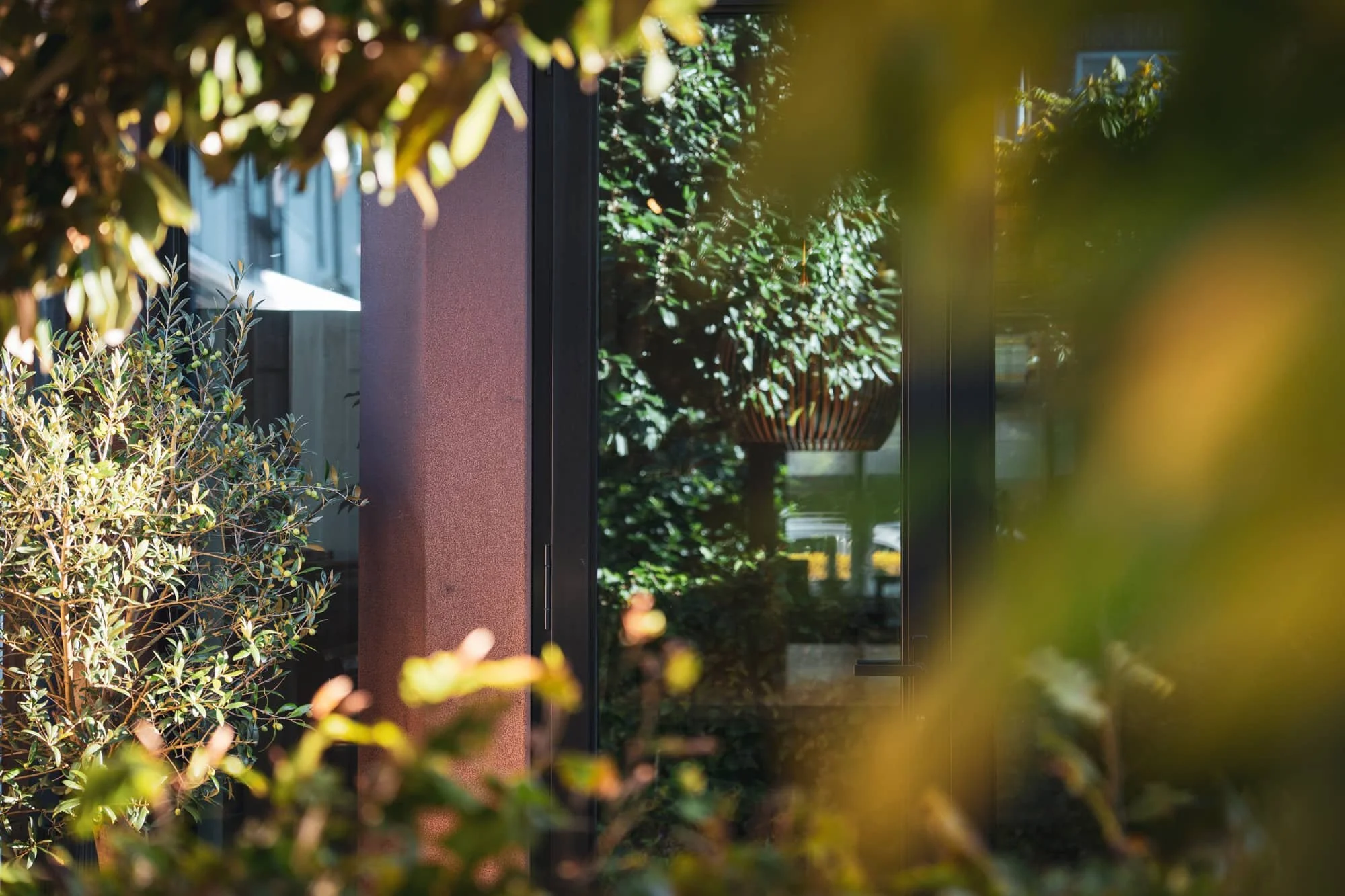 Corten steel column detail framed by foliage, Vondellaan, Rijswijk