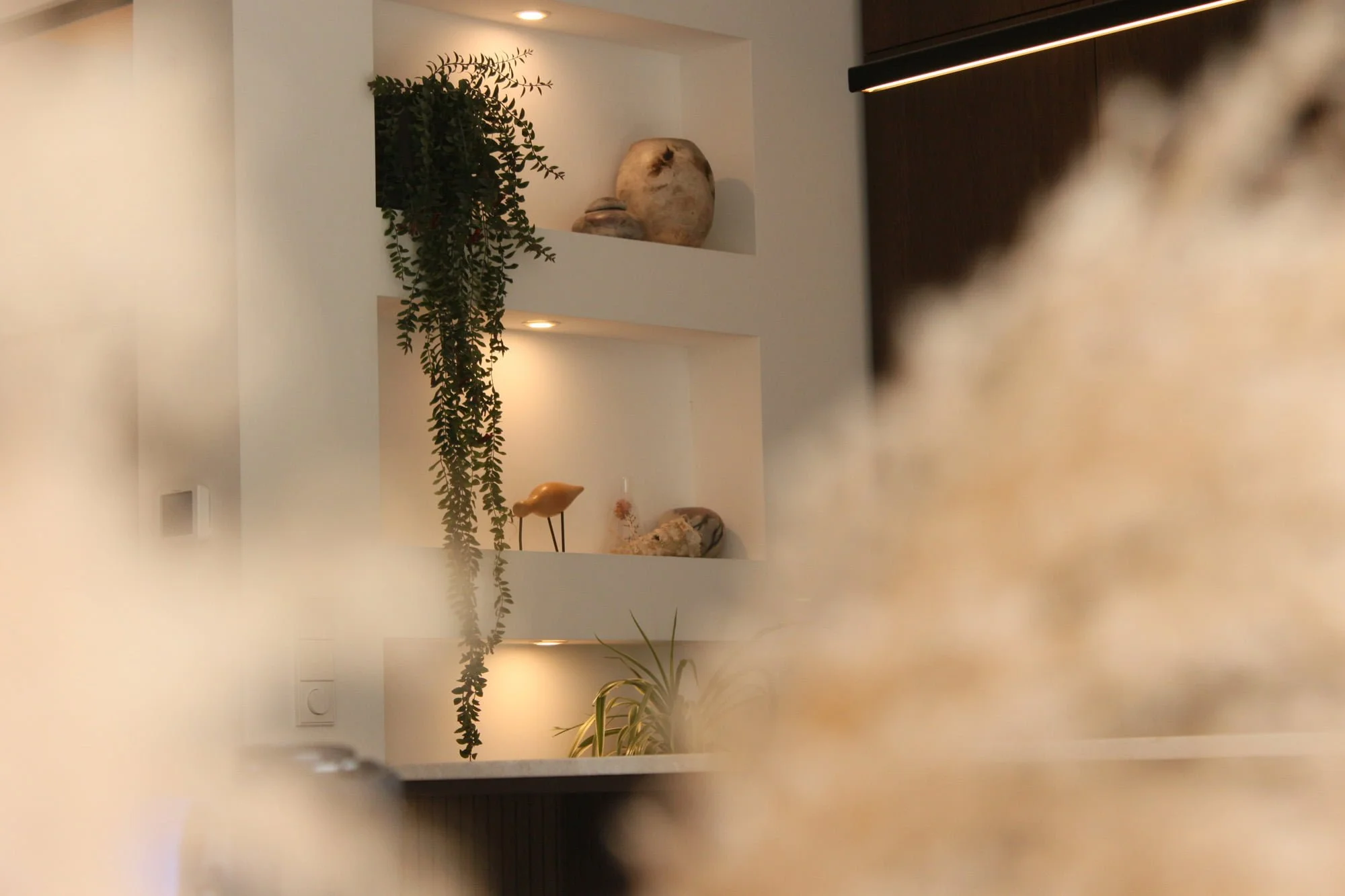 Integrated wall niches with warm lighting, greenery and refined interior styling details