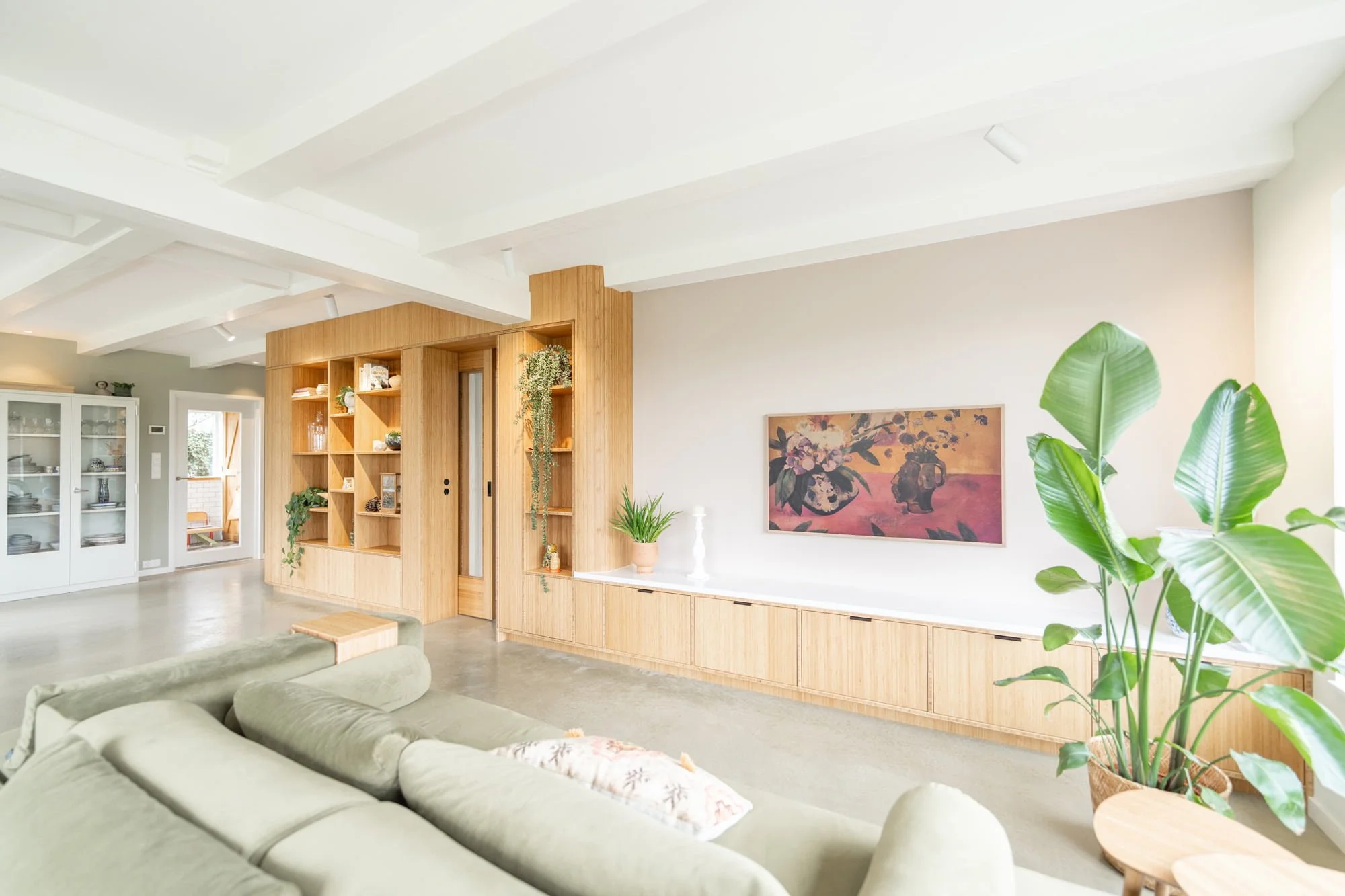 Living room with curved oak cabinetry, green sofa and warm natural textures