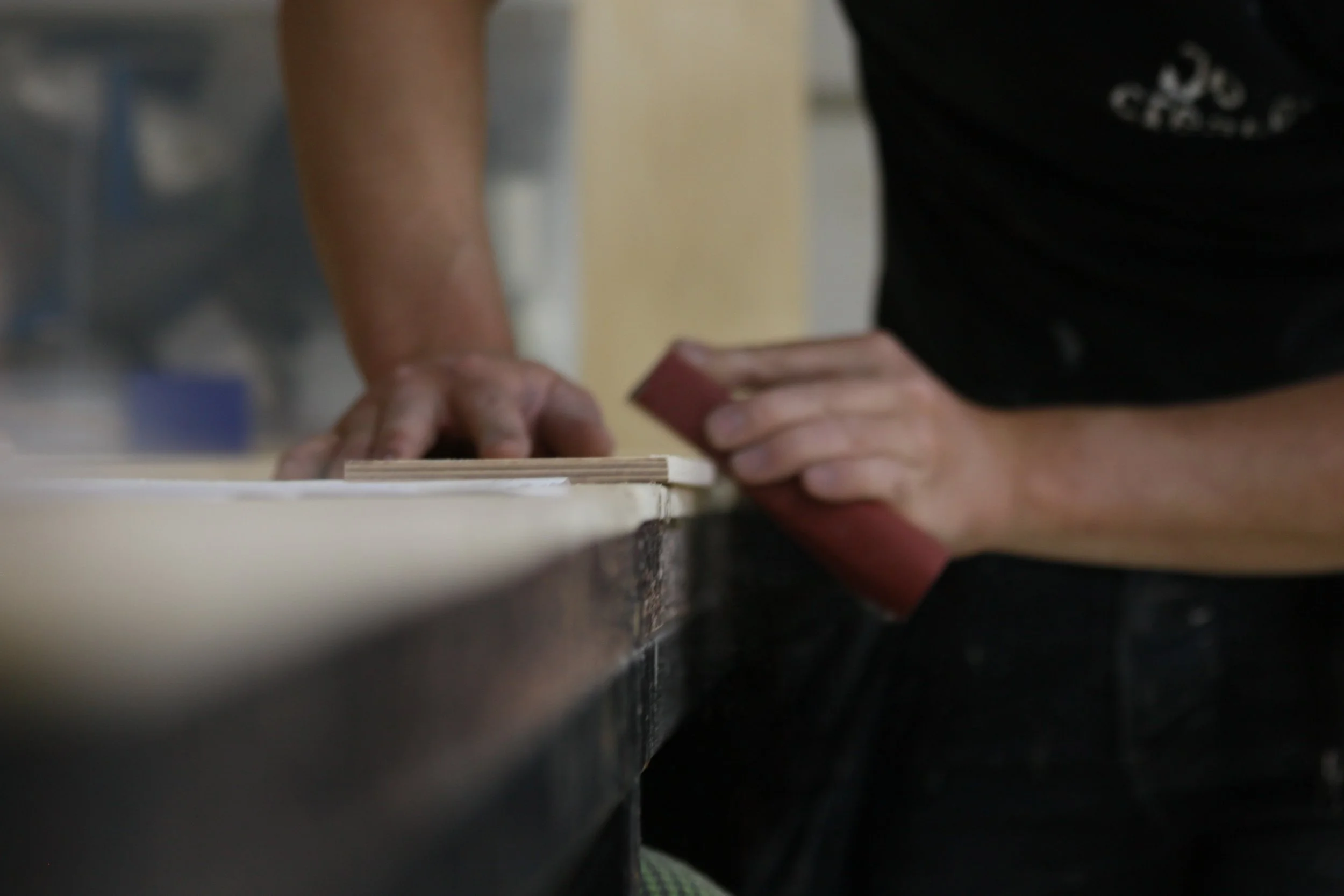 Close-up of someone working with their hands on a surface, possibly in a workshop or classroom setting.