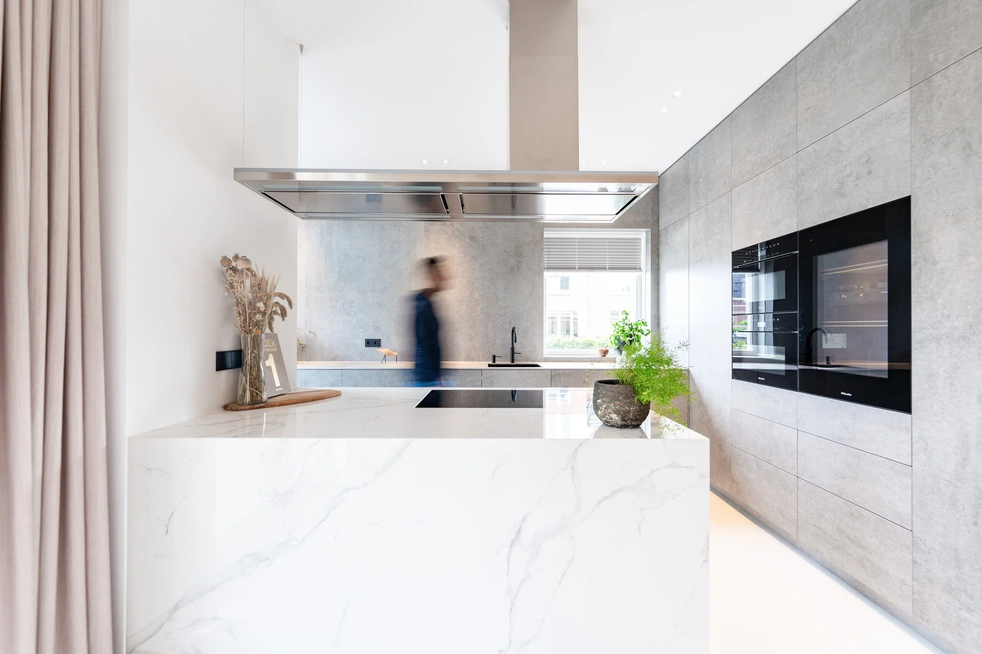 Minimal white kitchen with marble effect island, stainless steel extractor and oak accents