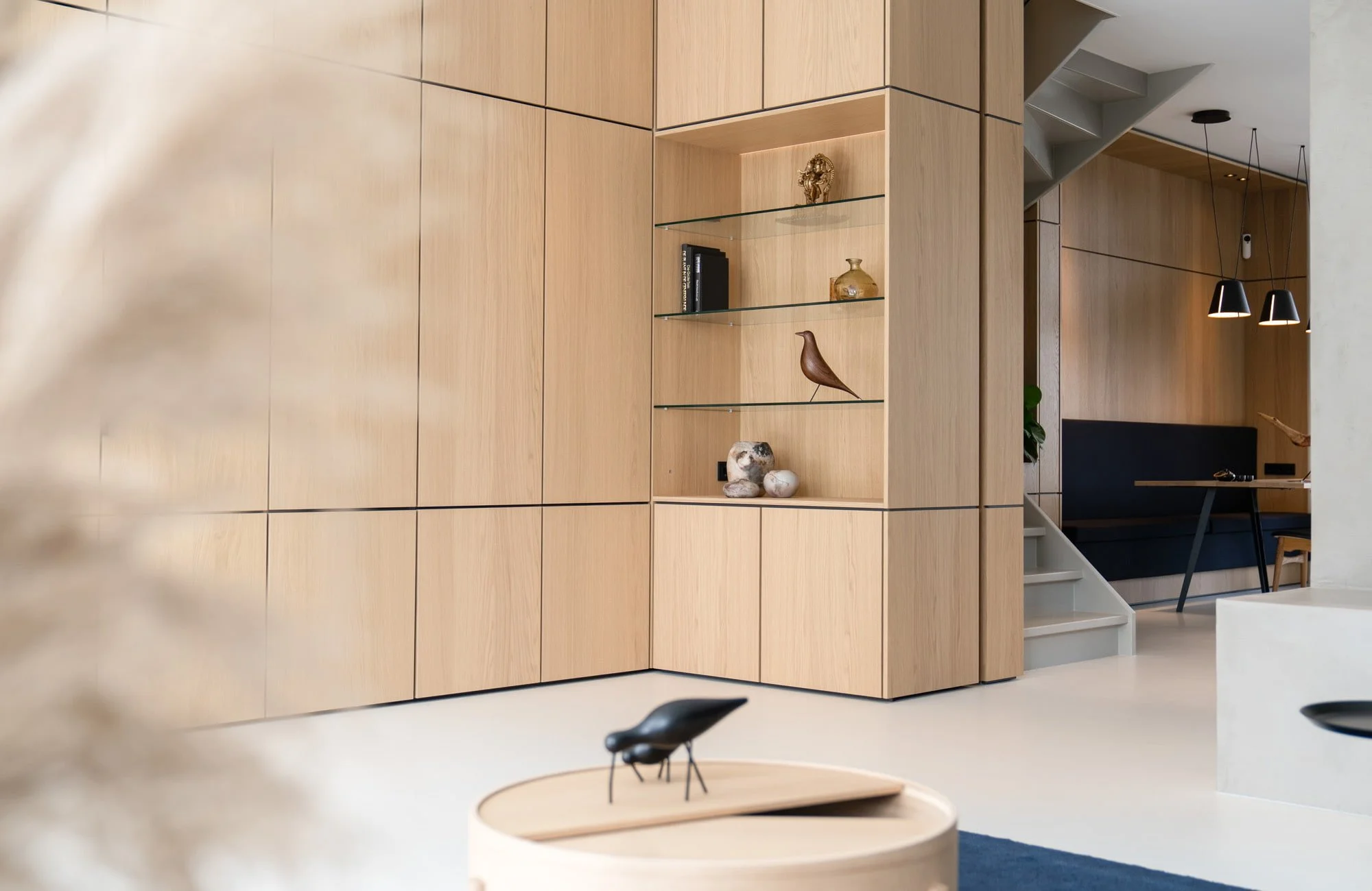 Bespoke oak storage wall with open shelving and soft neutral living room design