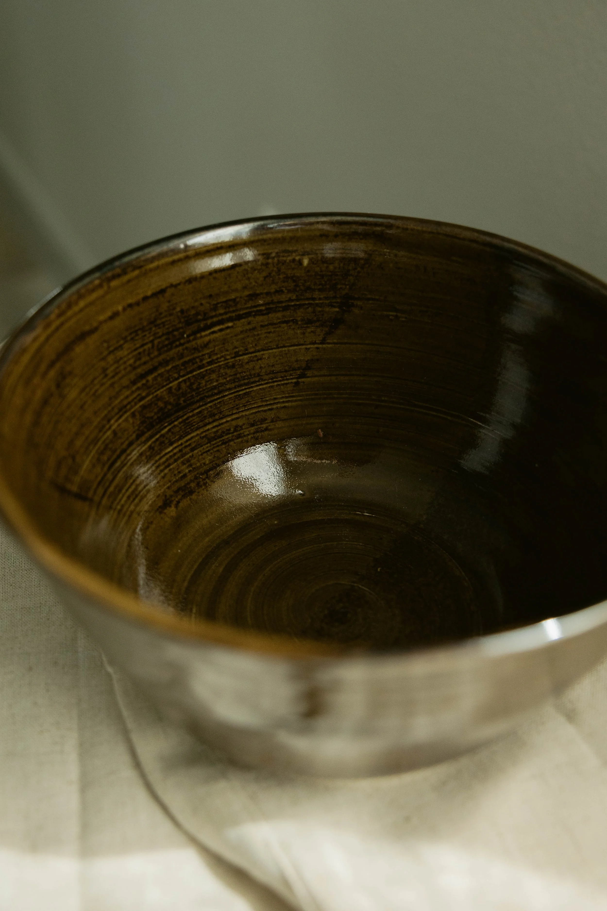 Close-up of a ceramic cup with brown and beige swirled inside, placed on a tiled surface.