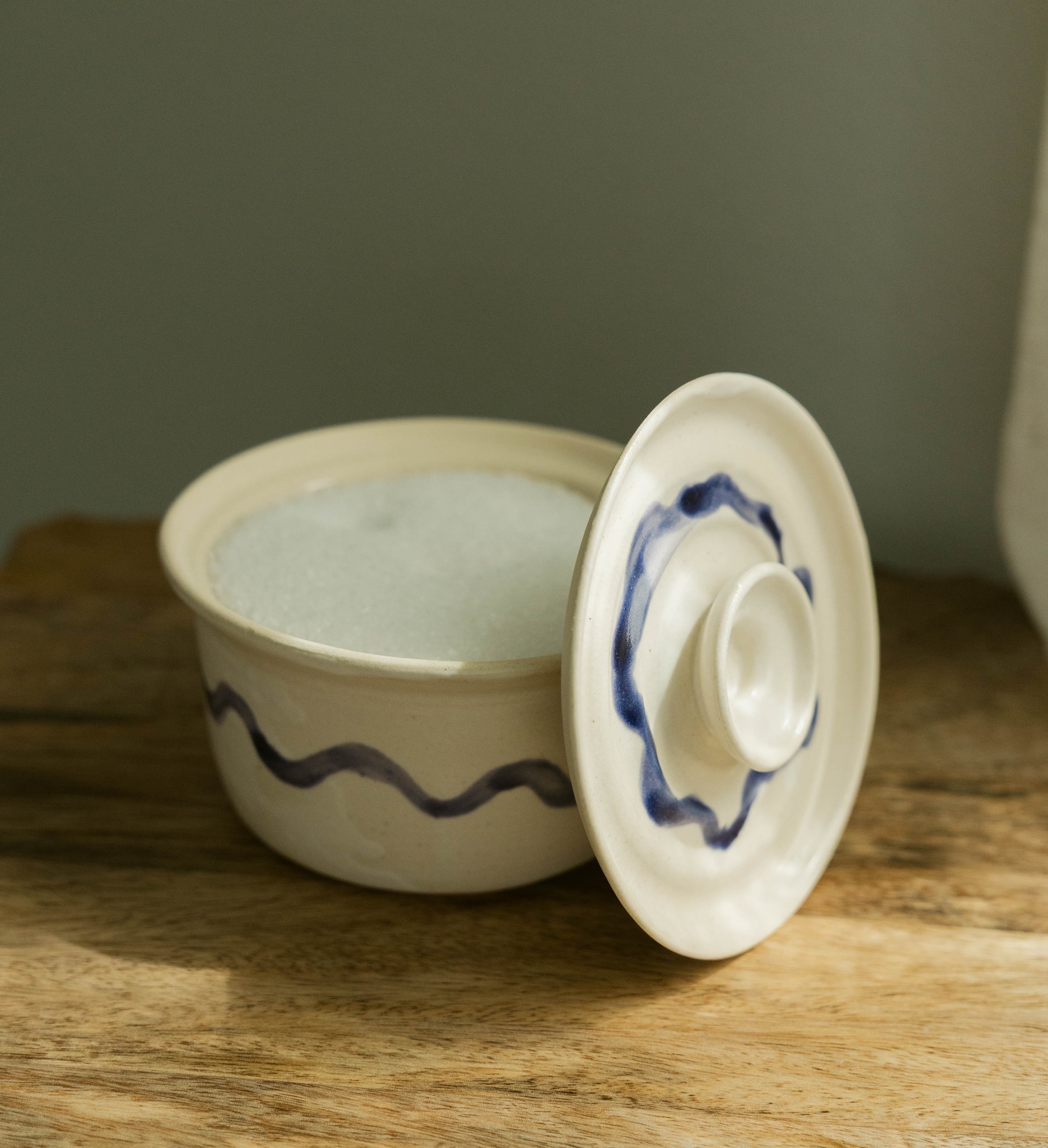 Close-up of three white ceramic cups with blue designs, stacked on a wooden surface against a plain background.