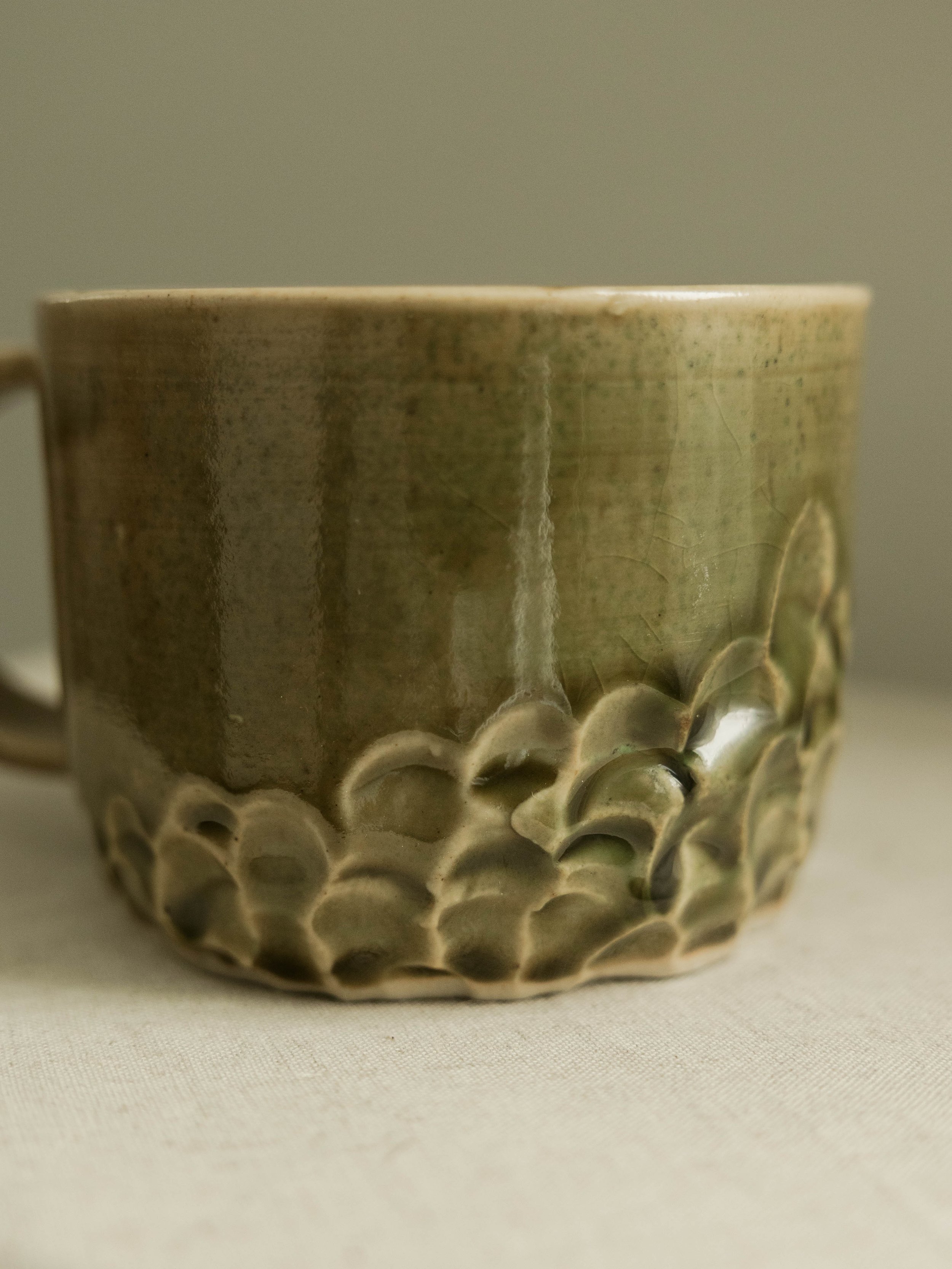 Close-up of a ceramic cup with a textured honeycomb-like pattern at the base and a smooth, glazed surface on the upper part.