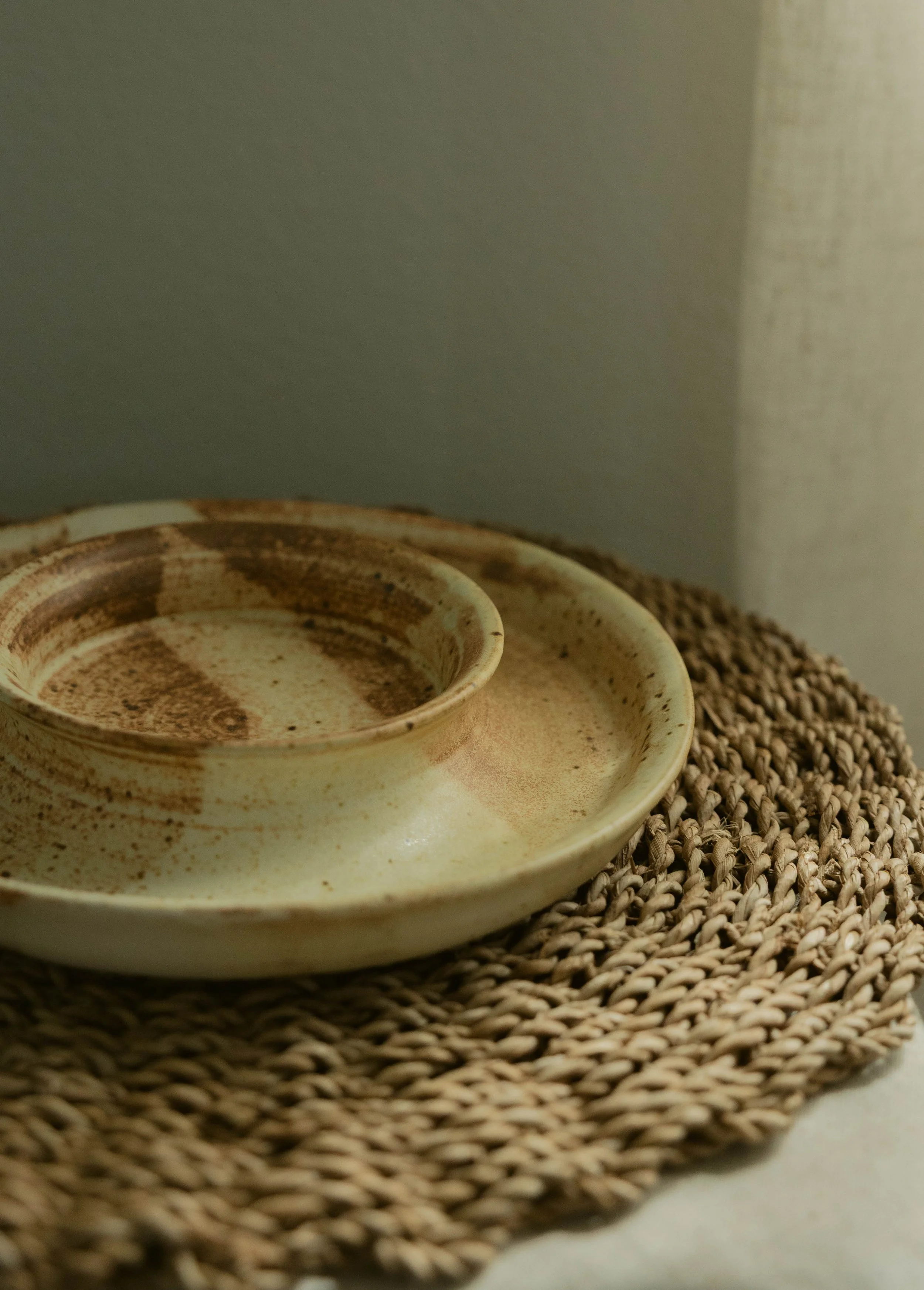 Close-up of a used coffee cup with brown residual coffee inside on a woven mat.