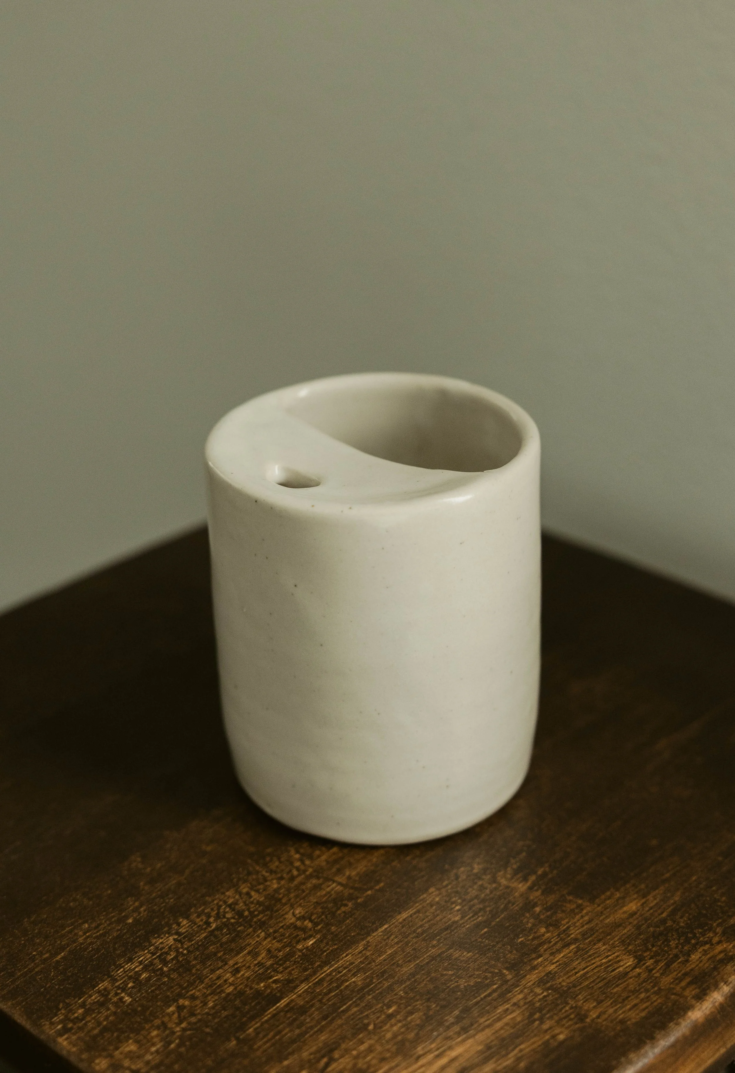 A white ceramic object on a dark wooden table