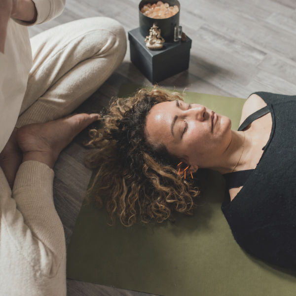 Woman resting on a yoga mat with 5NP ear needles in place.