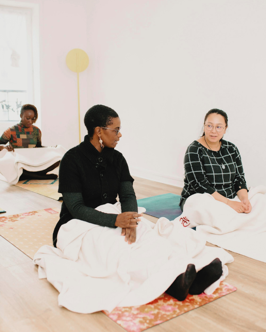 Participants seated together on yoga mats and blankets during a group wellness experience.