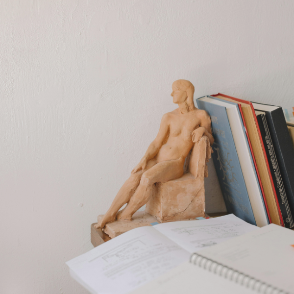 Small anatomical figure beside a row of books and an open notebook.