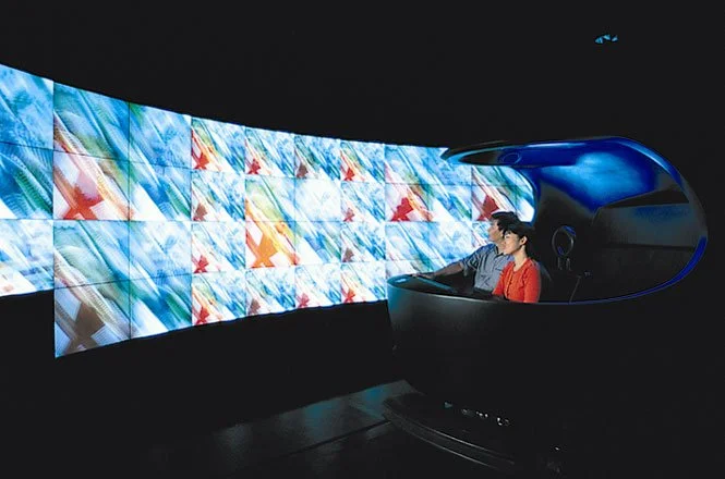 To bring visitors past a concert hall and up one floor, a custom built people-mover was created. It looped so that at the end of the visit, guest's returned to the entry point. Each leg had three or four media environments enhanced by a luxury-car-gr