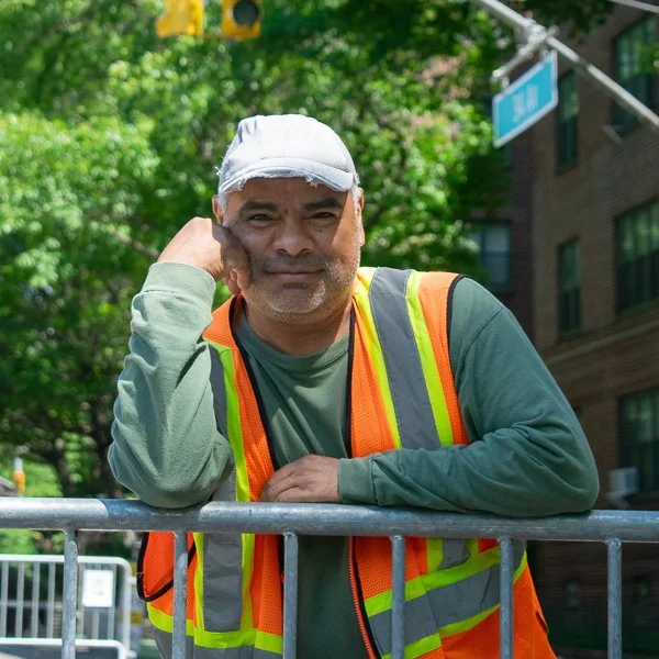 Community worker leaning against a barricade on a city street