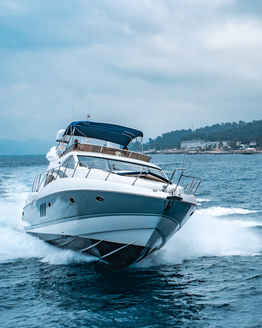 White powerboat speeding across the water near a coastal shoreline