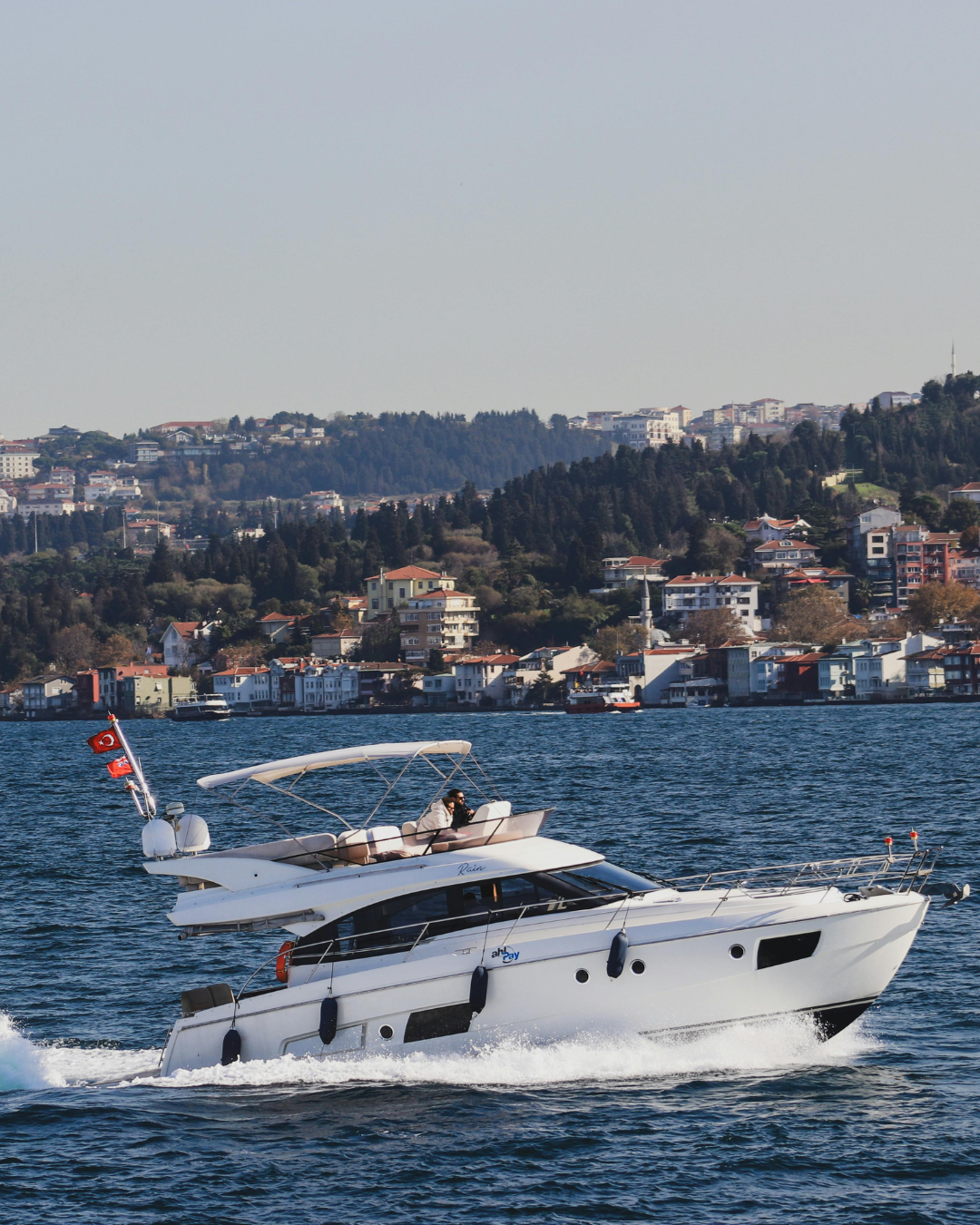 Motor yacht cruising past a colorful coastal town