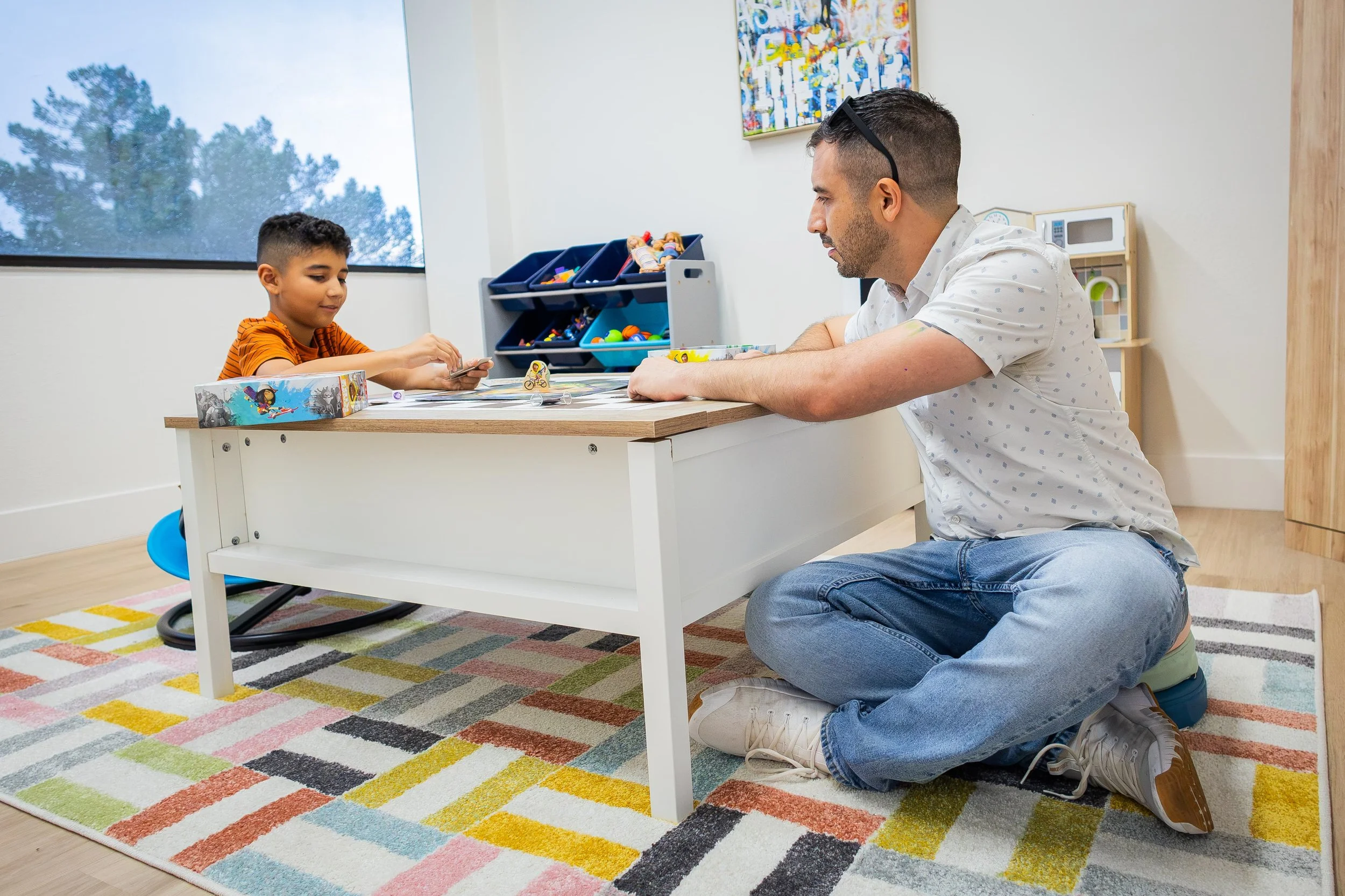Anthony Esquibel consulting young boy while playing in dedicated child space.