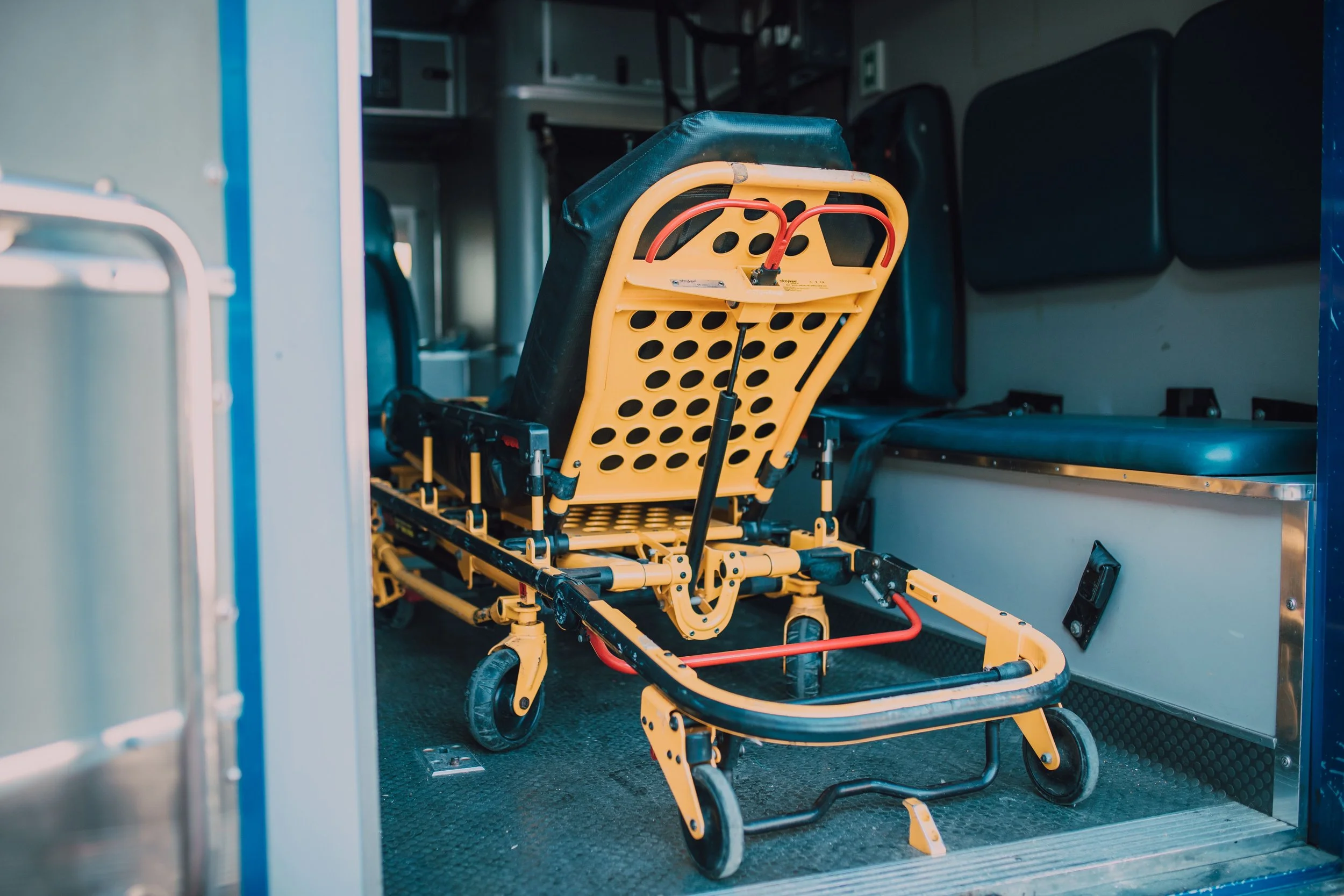 A yellow wheelchair parked inside an ambulance with its backrest and footrests visible.