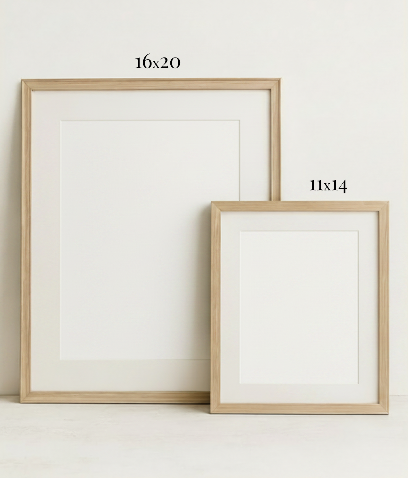 Two empty picture frames with natural wood borders, one larger (16x20 inches) and one smaller (11x14 inches), leaning against a plain white wall.