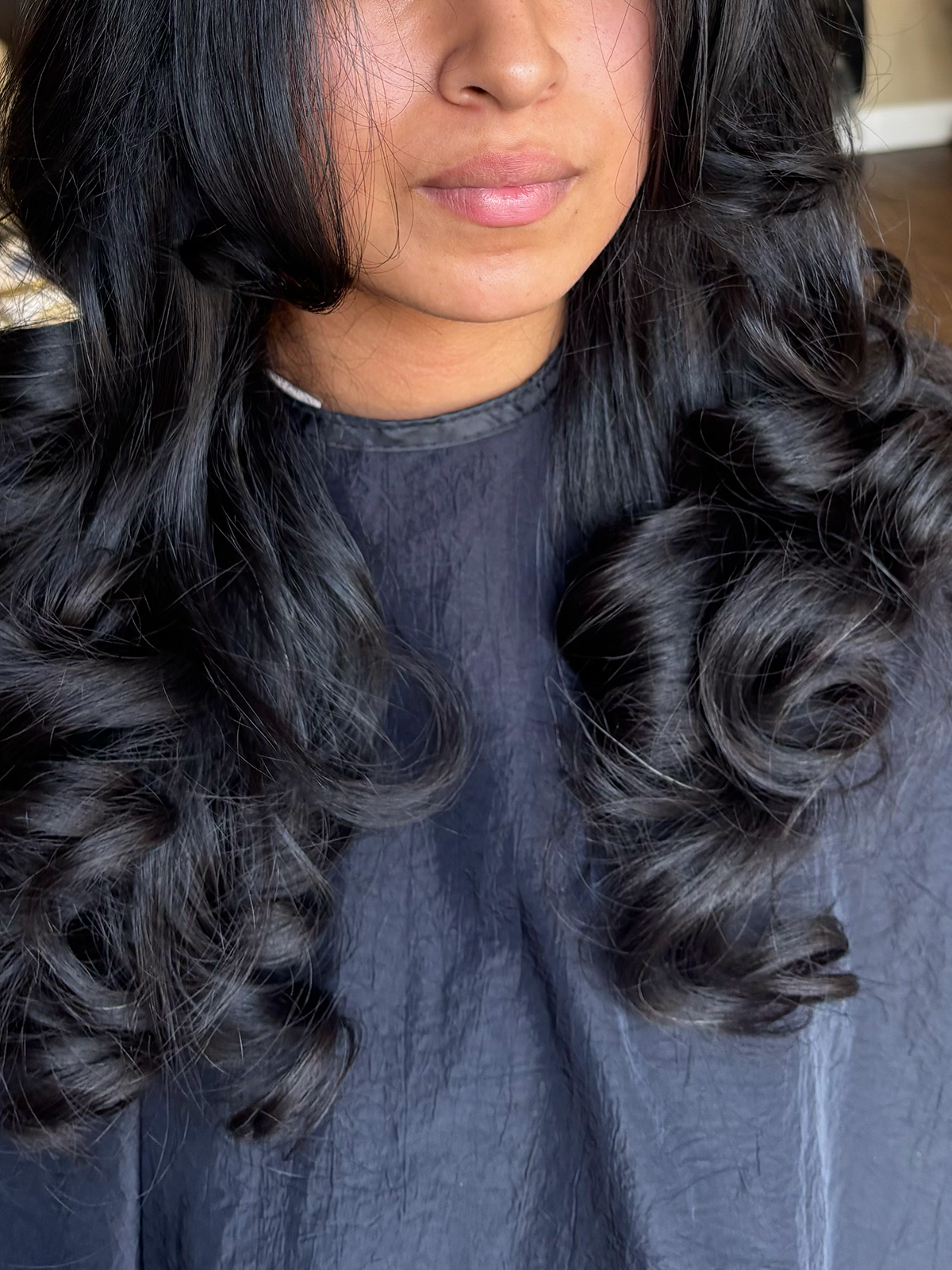 Close-up of a woman with long, shiny, black, curly hair