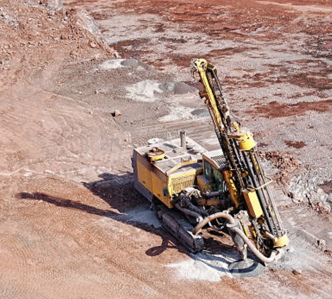 A large yellow drilling machine at a construction site on a dirt surface.