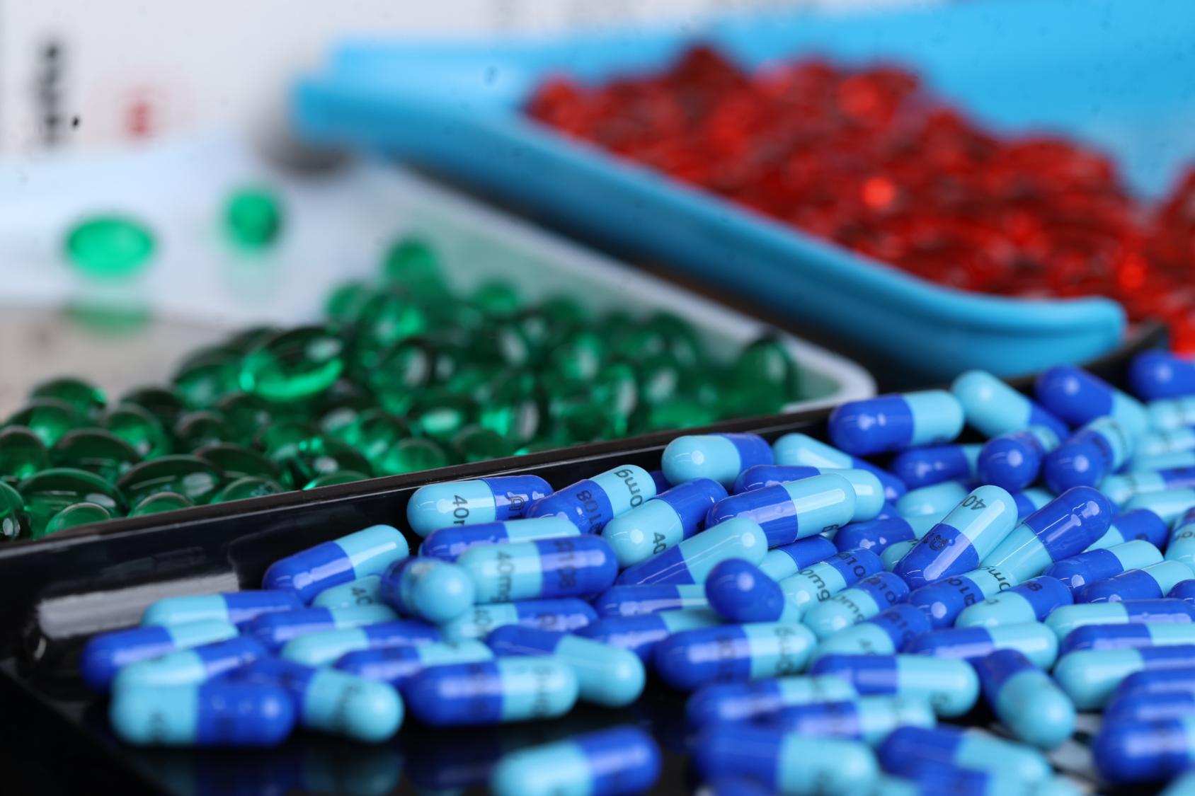 image of three trays with green, blue, and red pills