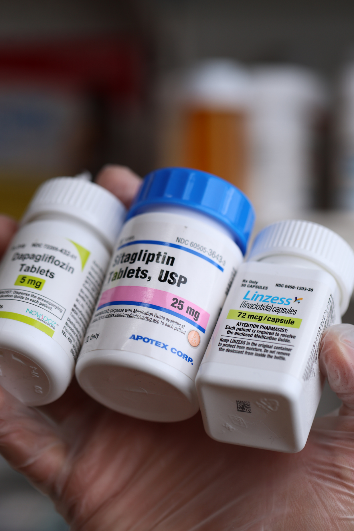 image of three medication bottles in someone's gloved hand