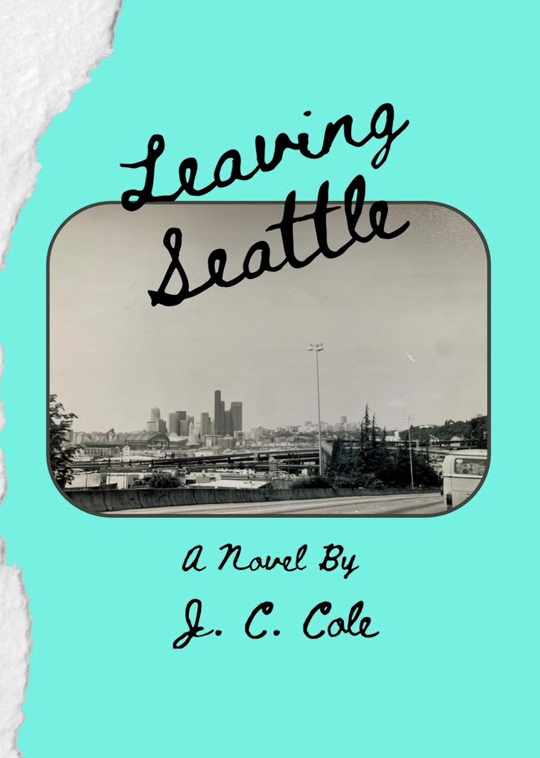 Book cover titled "Leaving Seattle: A Novel by J. C. Cole" with a black and white photo of Seattle skyline and highway in the background, turquoise border, torn paper effect on top left corner.