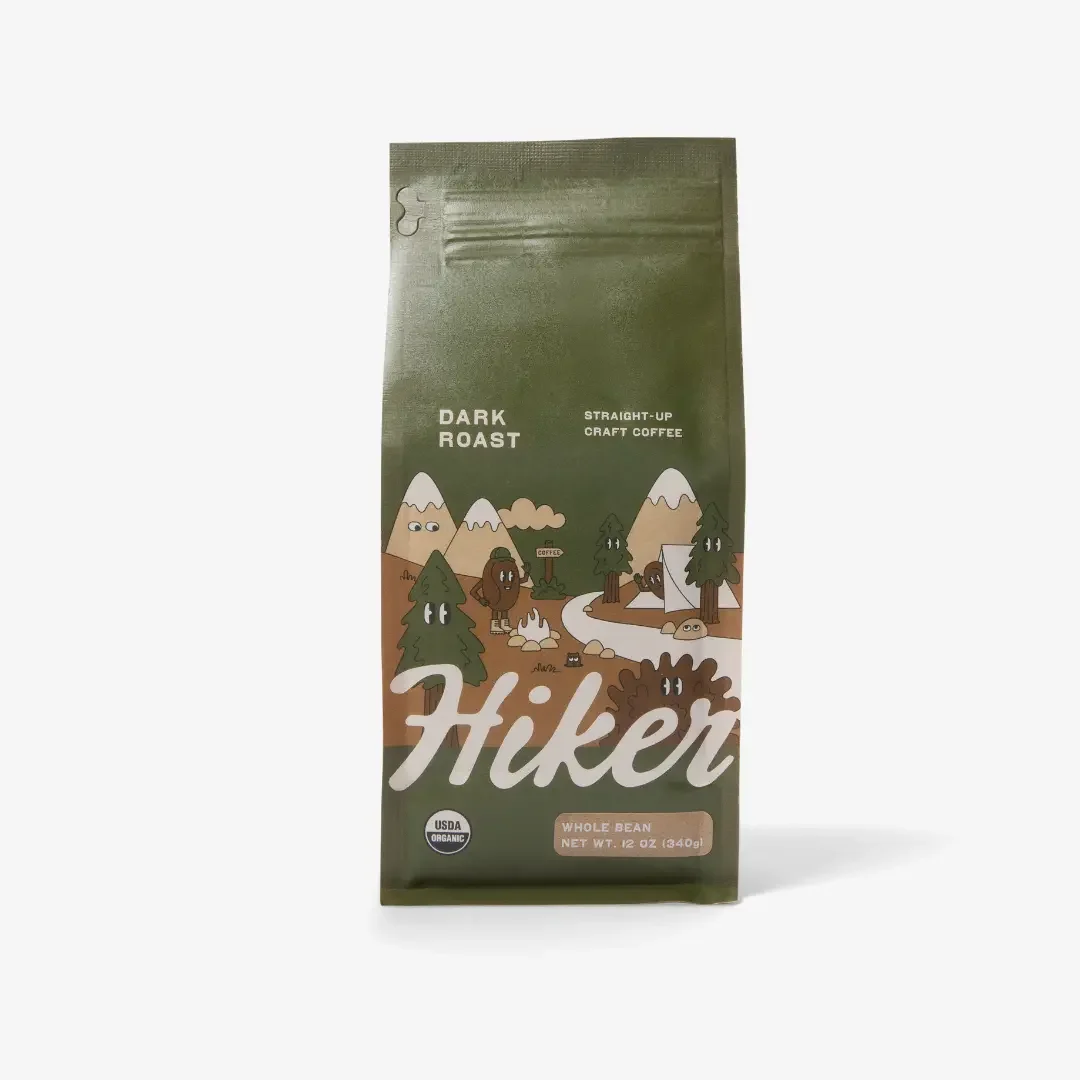 Green paper bag of whole coffee beans against a white background