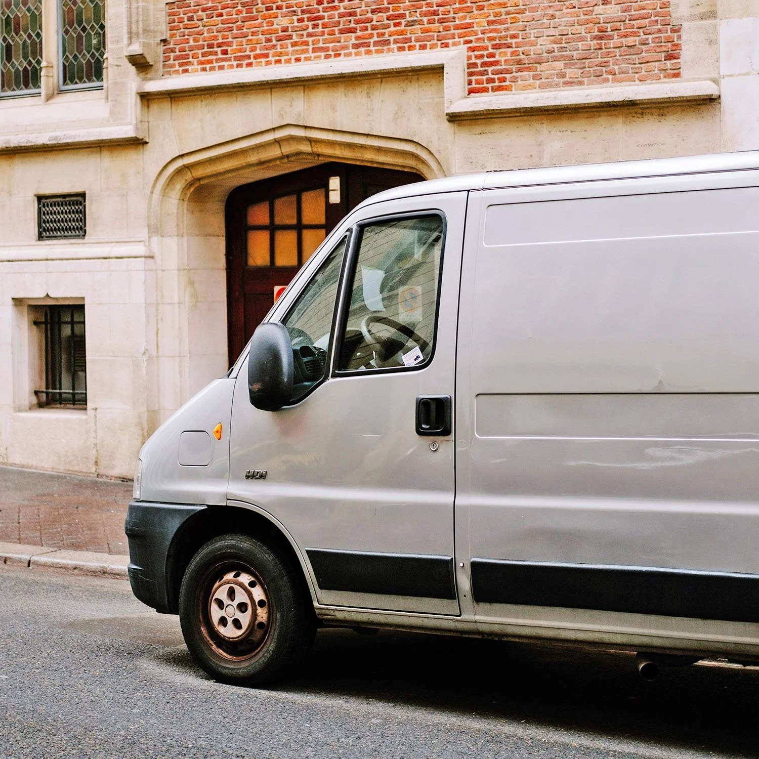 A white van waits outside of a building to transport visually impaired or blind individuals.