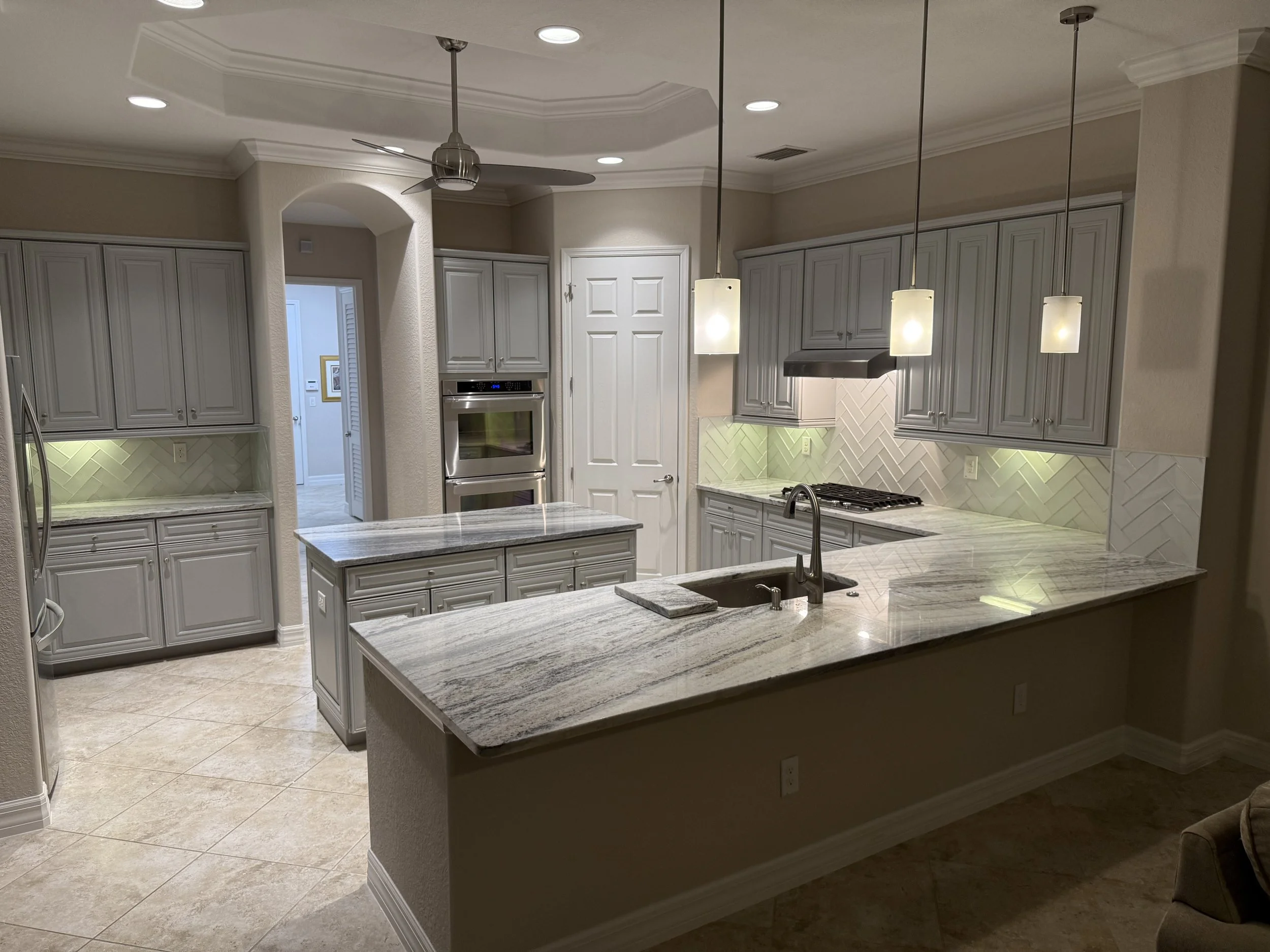 Kitchen with white cabinets, granite countertops, and pendant lights.