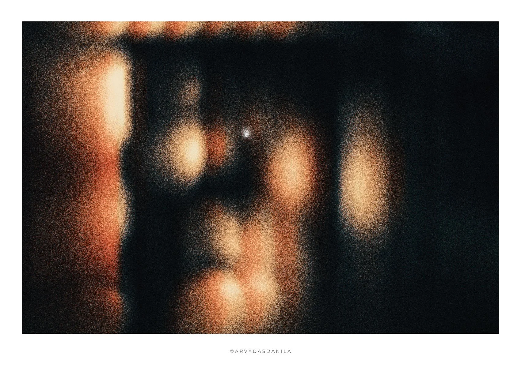 Abstract, blurred artistic image with warm colors, dark background, and signature at the bottom.
