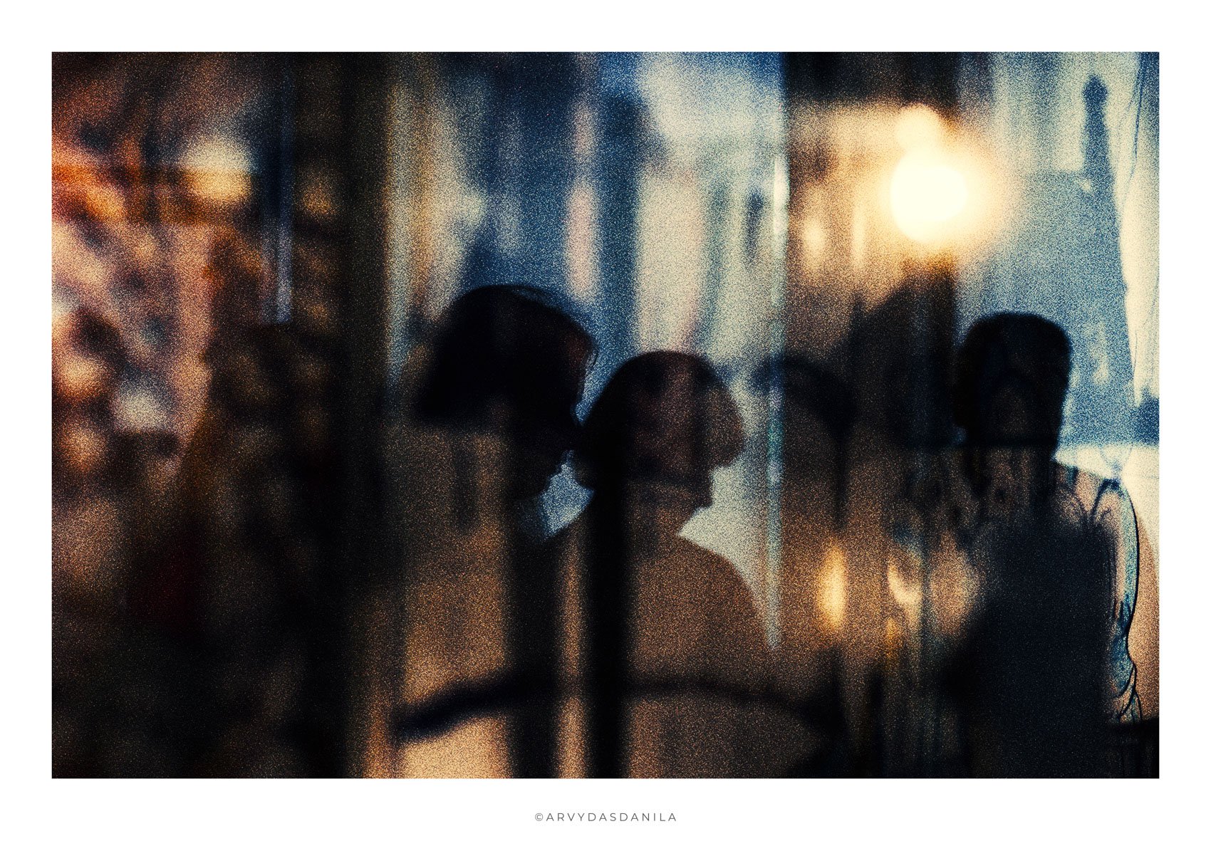 Blurred silhouette of multiple people standing together against a background of warm sunlight and reflections, creating an artistic and abstract scene.