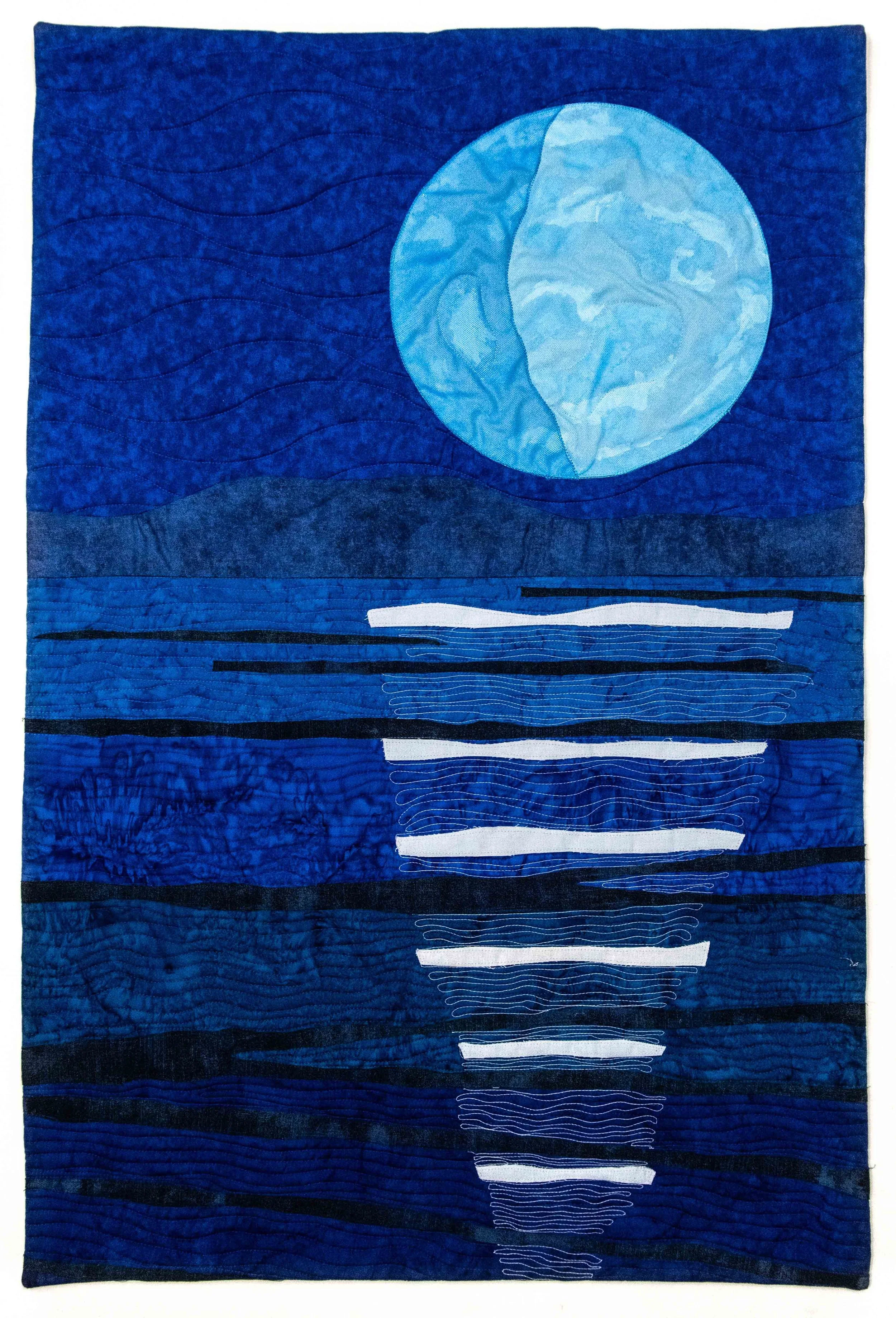 Quilt with a blue background, a large moon and a sailboat in a body of water, using various shades of blue and black.