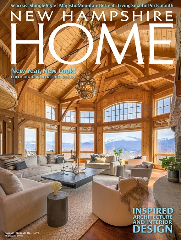 Interior of a spacious wooden living room with large windows overlooking a mountain view, decorated with neutral-colored sofas, armchairs, and a coffee table.