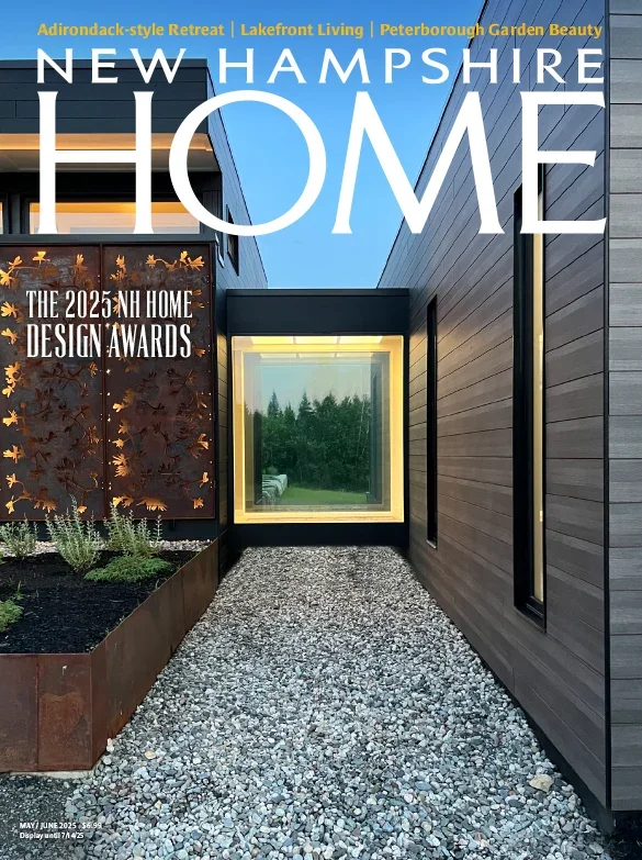 Cover of New Hampshire Home magazine featuring a modern house exterior with a gravel pathway, wooden siding, and a decorative metal panel with leaf cutouts, highlighting the 2025 NH Home Design Awards.