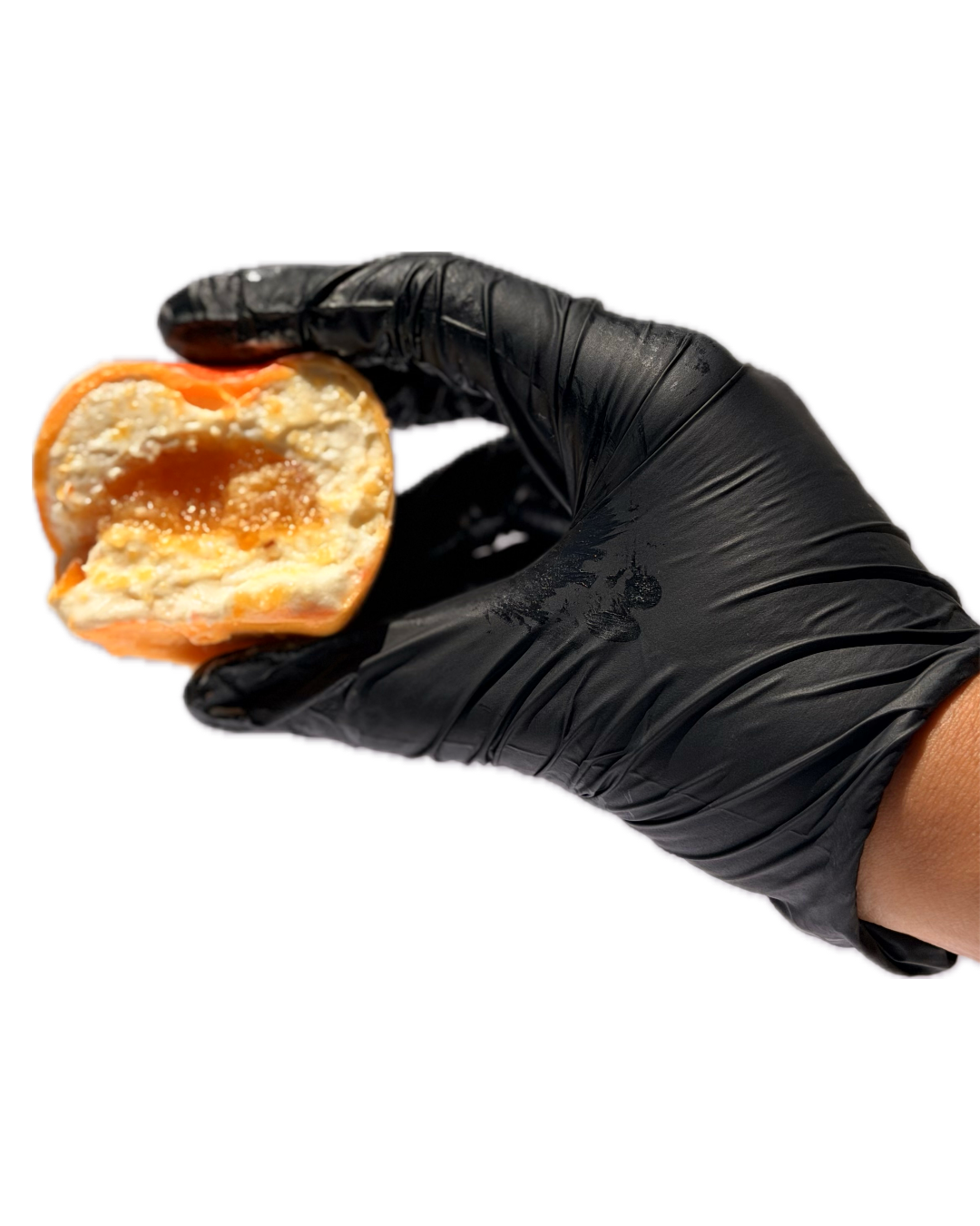 A hand in a black glove holding a partially eaten snack with a peach-colored wrapper, showing a creamy filling and orange sauce inside.