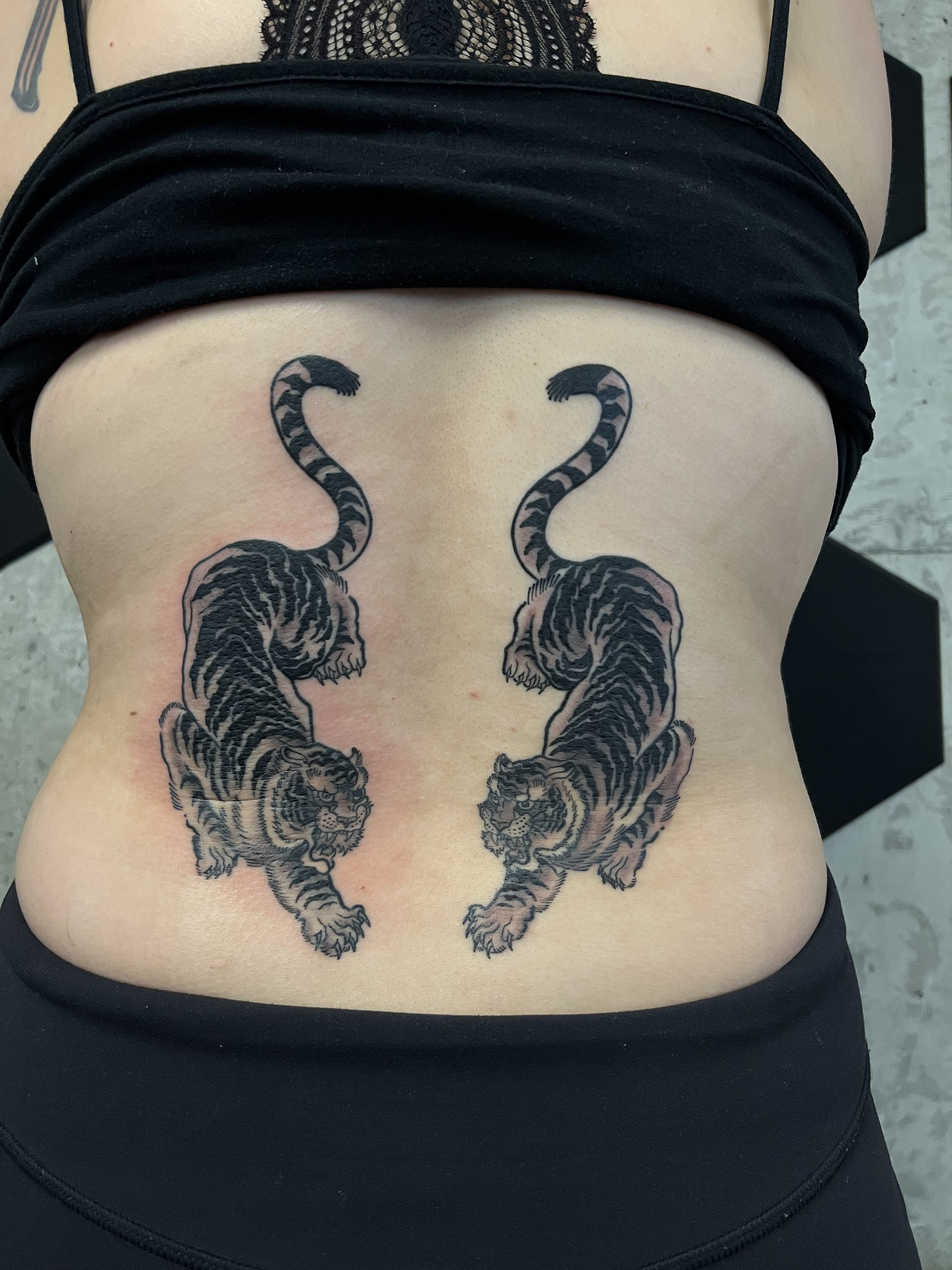 Tattoo of two tigers facing each other on a person's lower back.