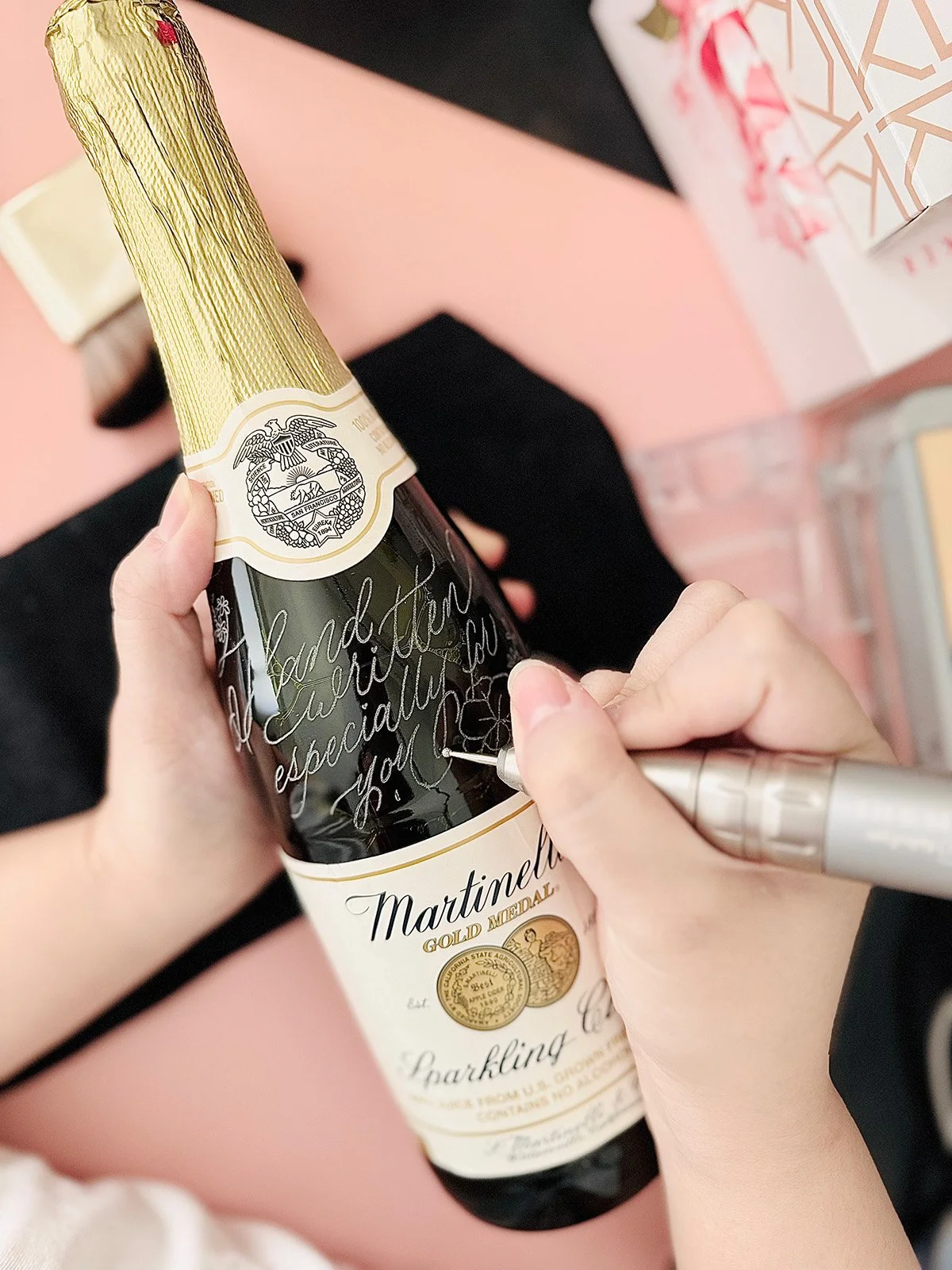 Person signing a bottle of Martinelli's sparkling apple cider with a silver marker.