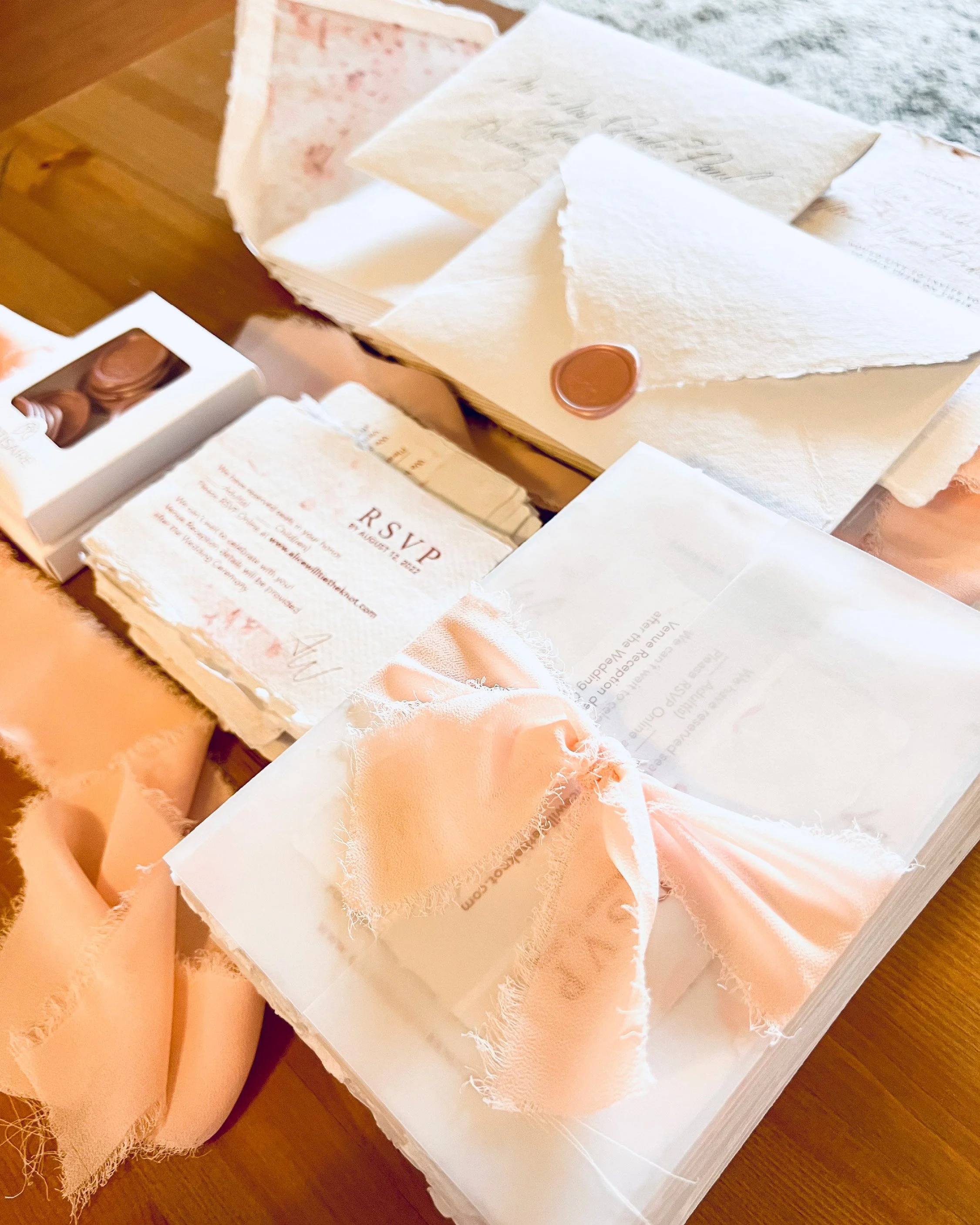 Close-up of various textured paper napkins and a wedding RSVP card on a wooden surface.