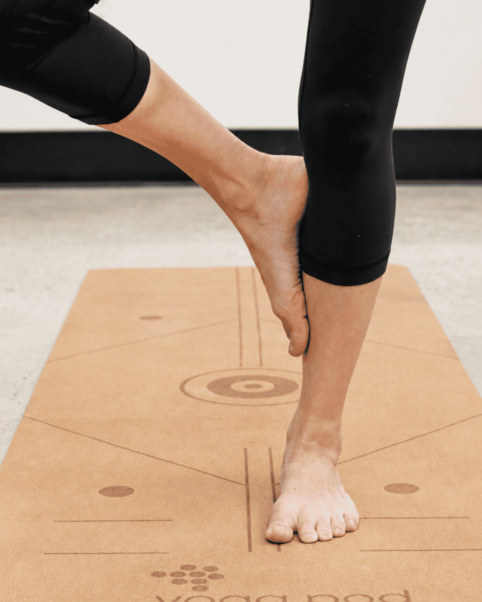 Person standing on yoga mat at yoga pod tucson.
