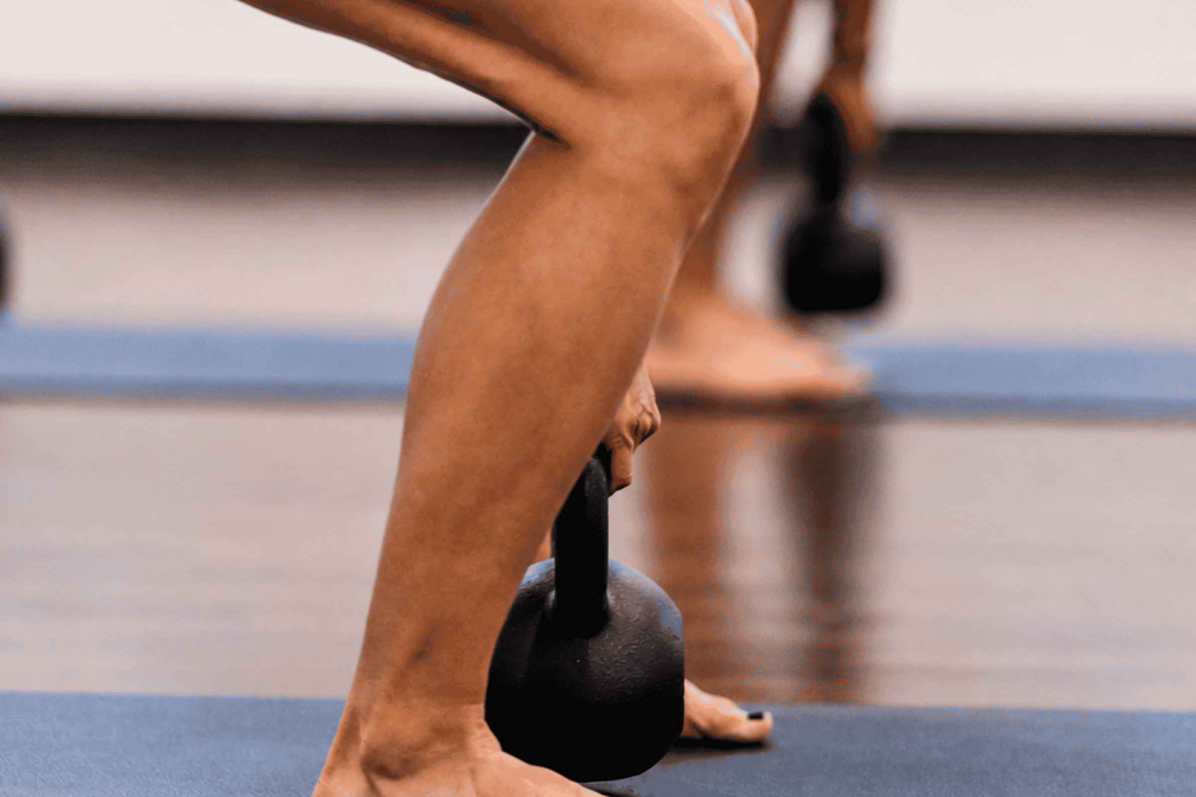 Close-up of a person's legs n a blue mat, with hands and feet visible, at yoga pod tucson.