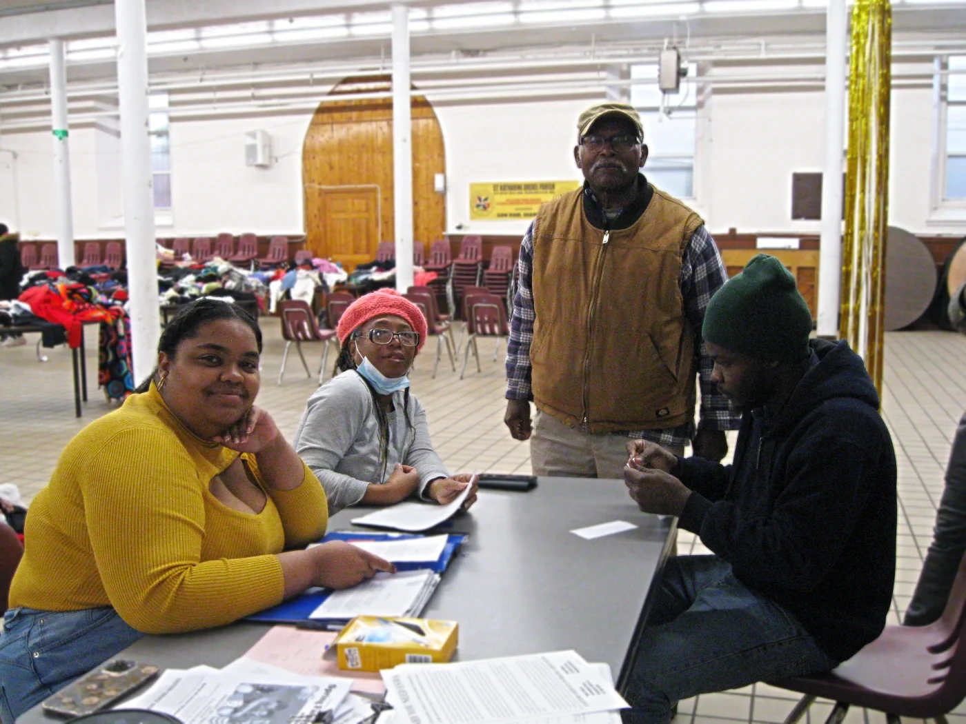 Photo of four members and volunteers in front of tables covered in clothes.
