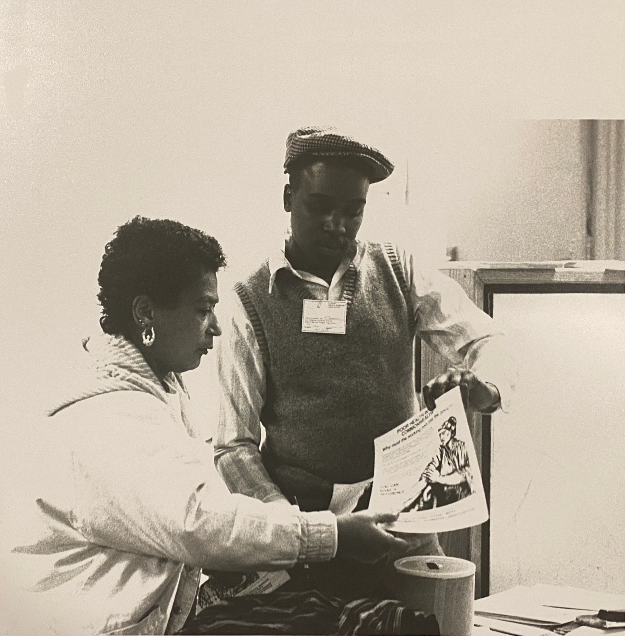 Black and white historic photo of an organizer showing a flyer to a member.