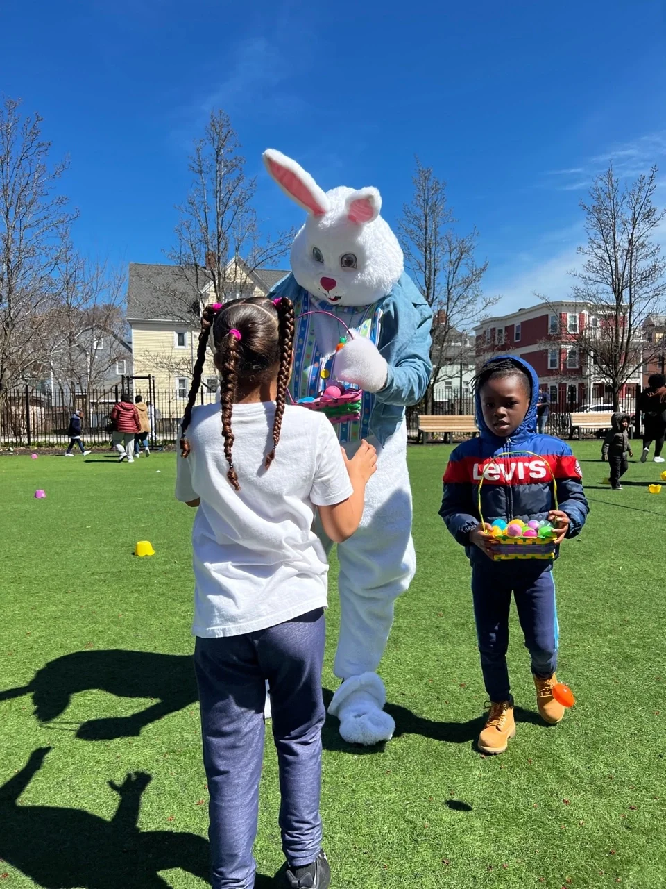 Two kids with a basket of Easter eggs with a volunteer dressed as the Easter Bunny.