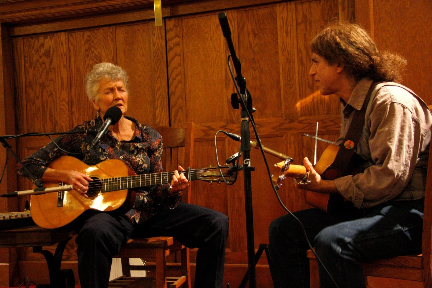 Photo of woman singing and playing guitar alongside another guitarist.