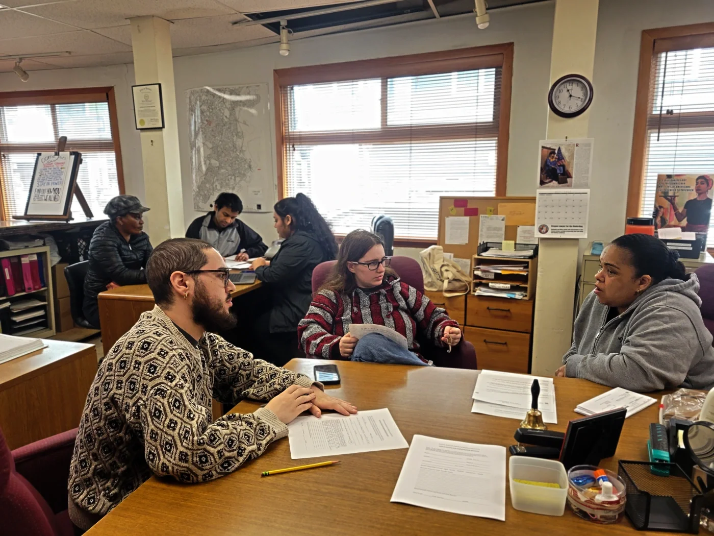 Photo showing two groups of volunteers and members in the ESWA office, with one volunteer listening to the member and the other taking notes in each group.