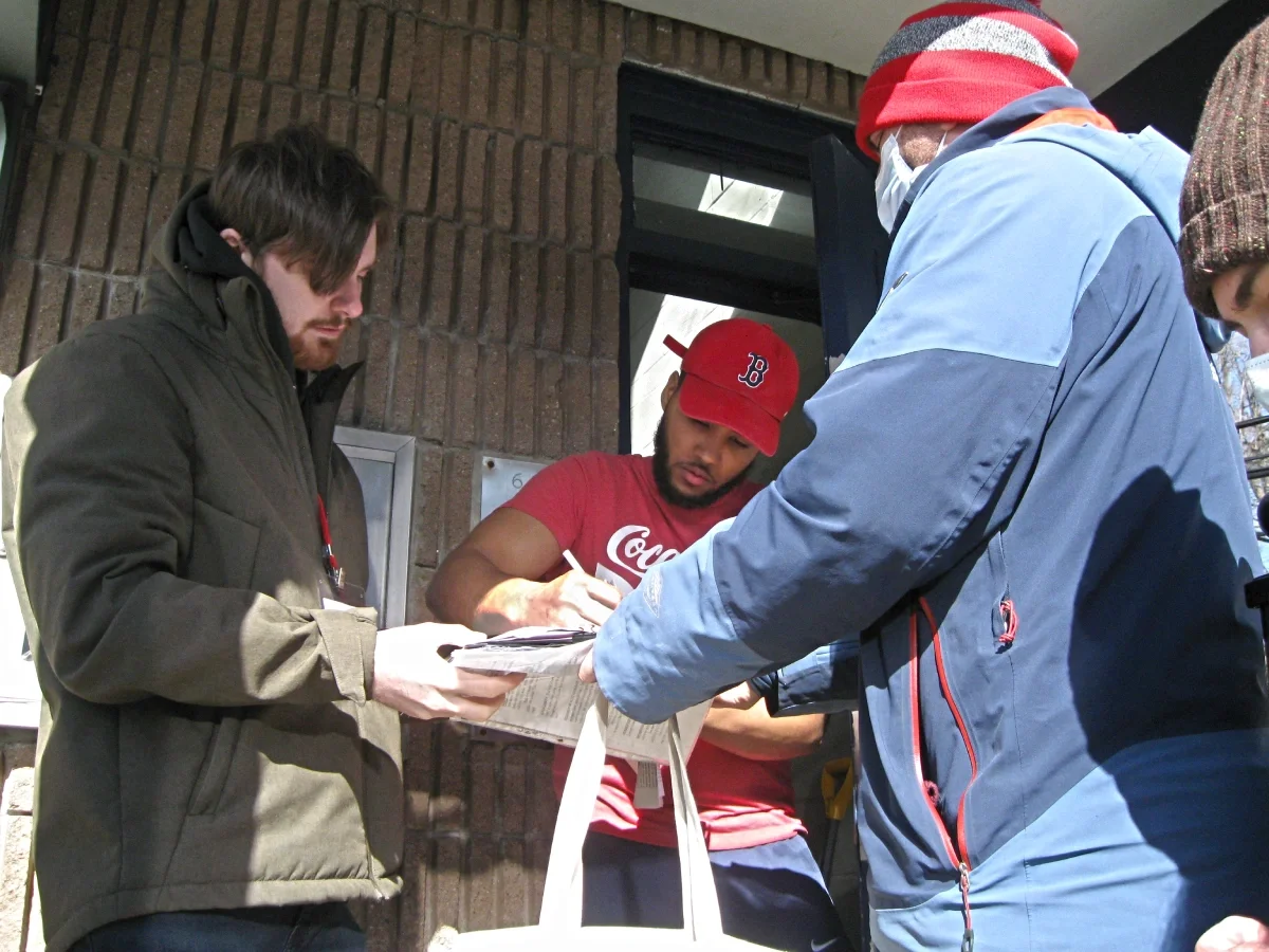 Two ESWA volunteers in winter coats signing up a member at his front door.