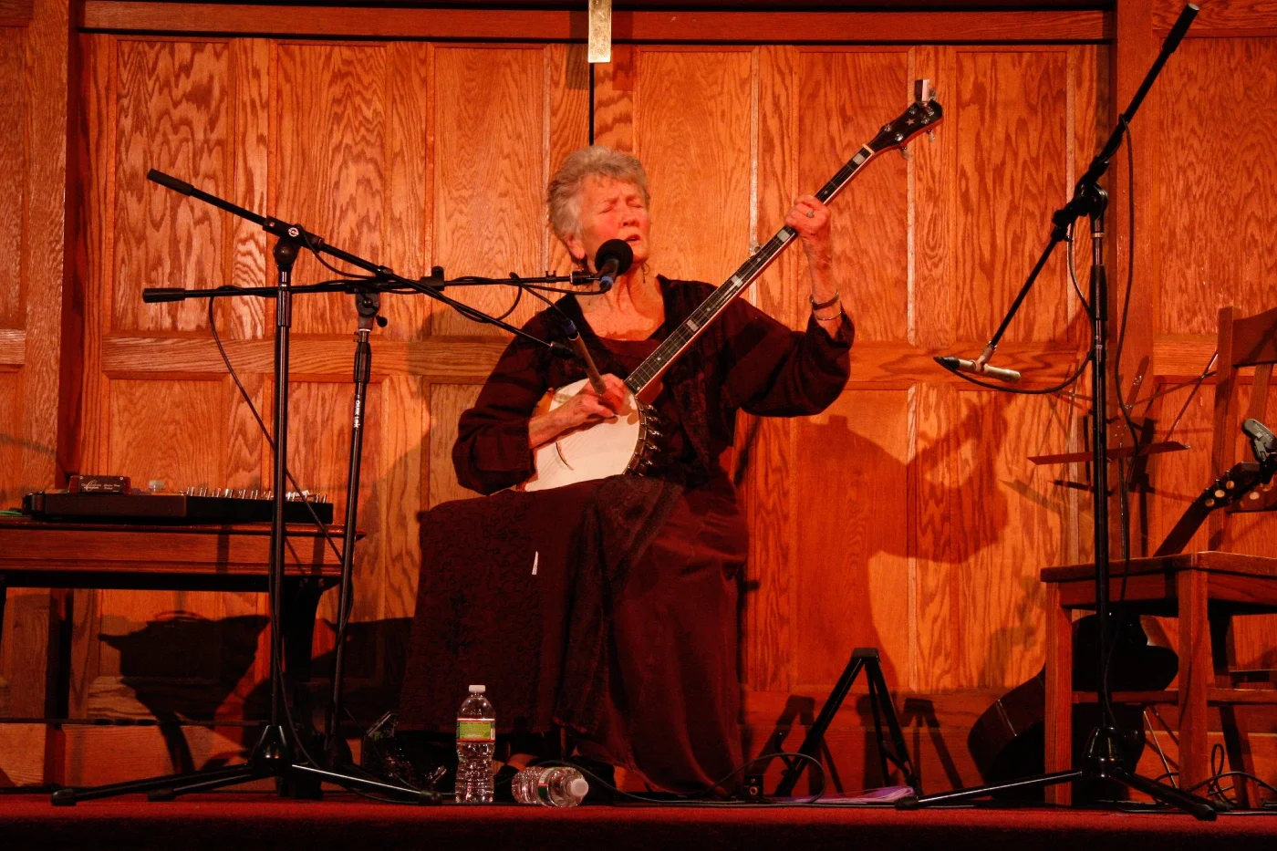 Photo of woman singing on stage playing banjo.
