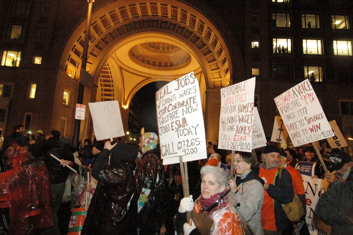 Photo of ESWA organizers at a protest holding signs, one reading "REAL JOBS W/ LIVING WAGES STOP CORPORATE WELFARE NOW JOIN ESWA TODAY"
