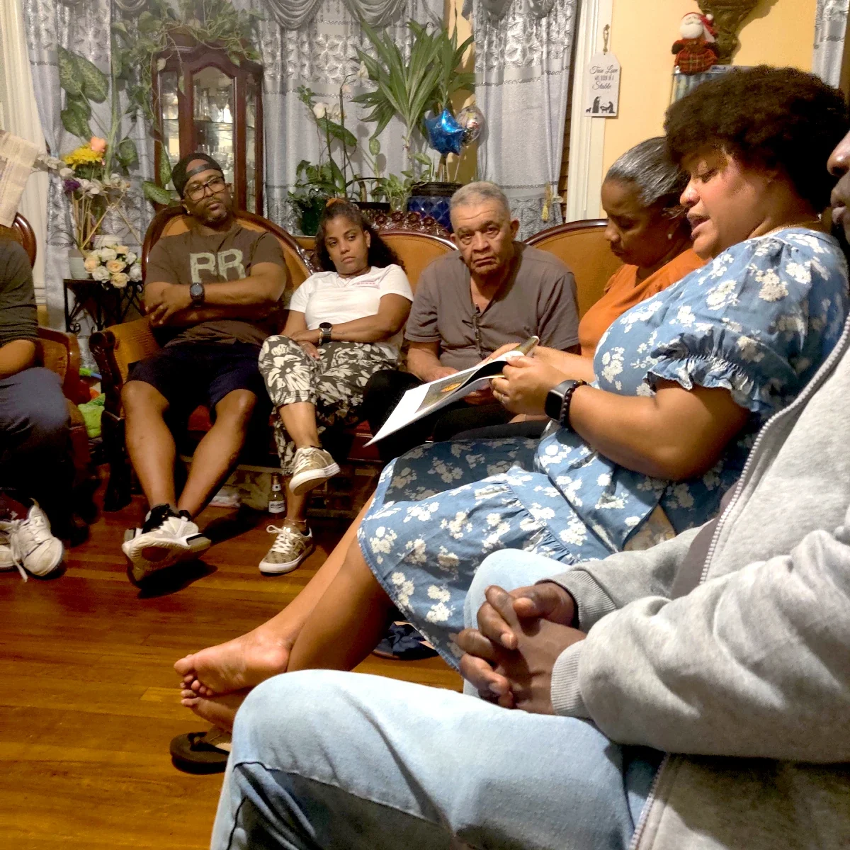 ESWA member reads aloud from a document as other members listen at a house meeting.