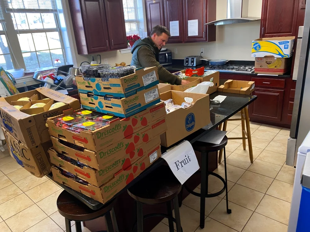 Volunteer sorting at a table covered in boxes of fruit.